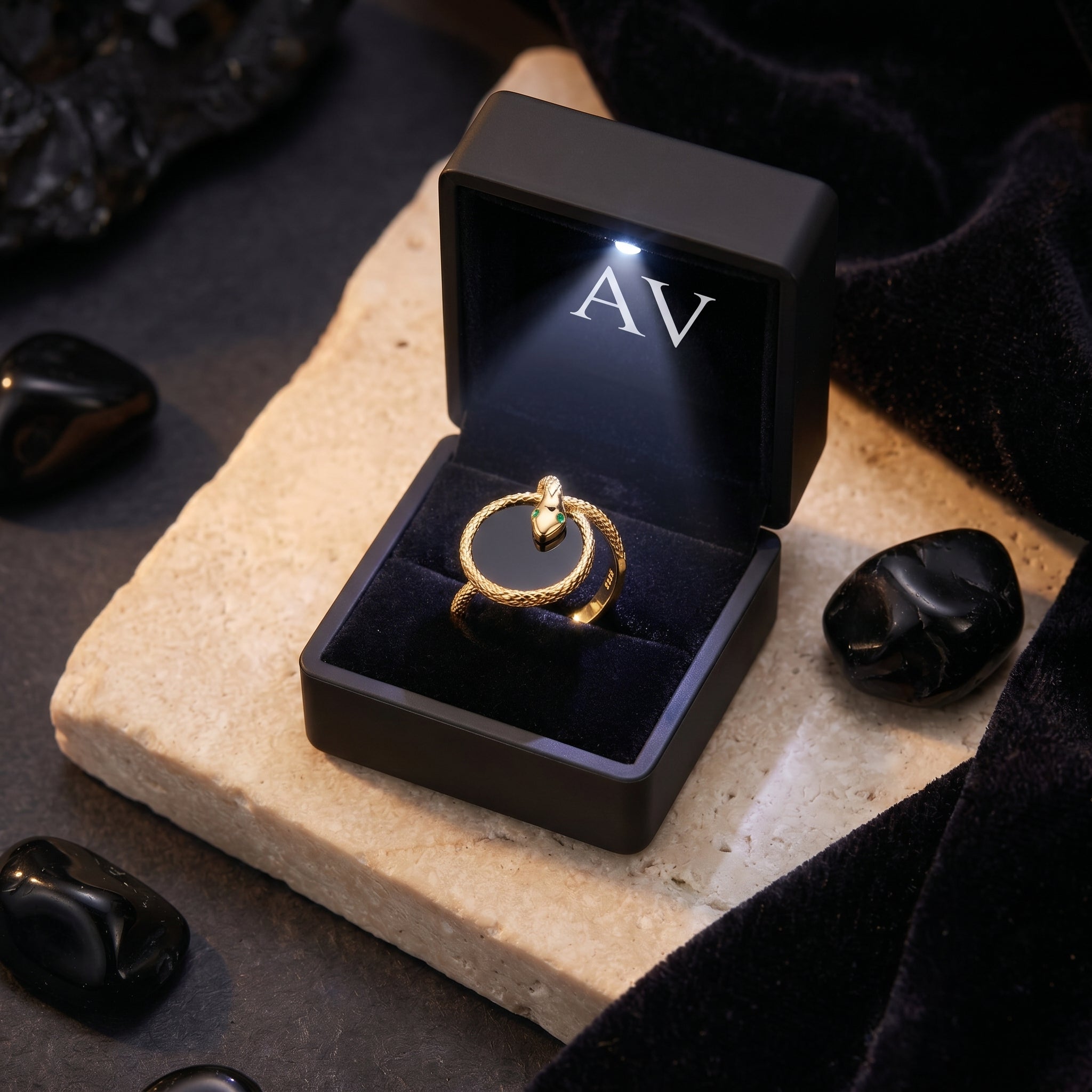 The Regalia gold plated onyx snake ring in a black LED-lit gift box with AV branding.