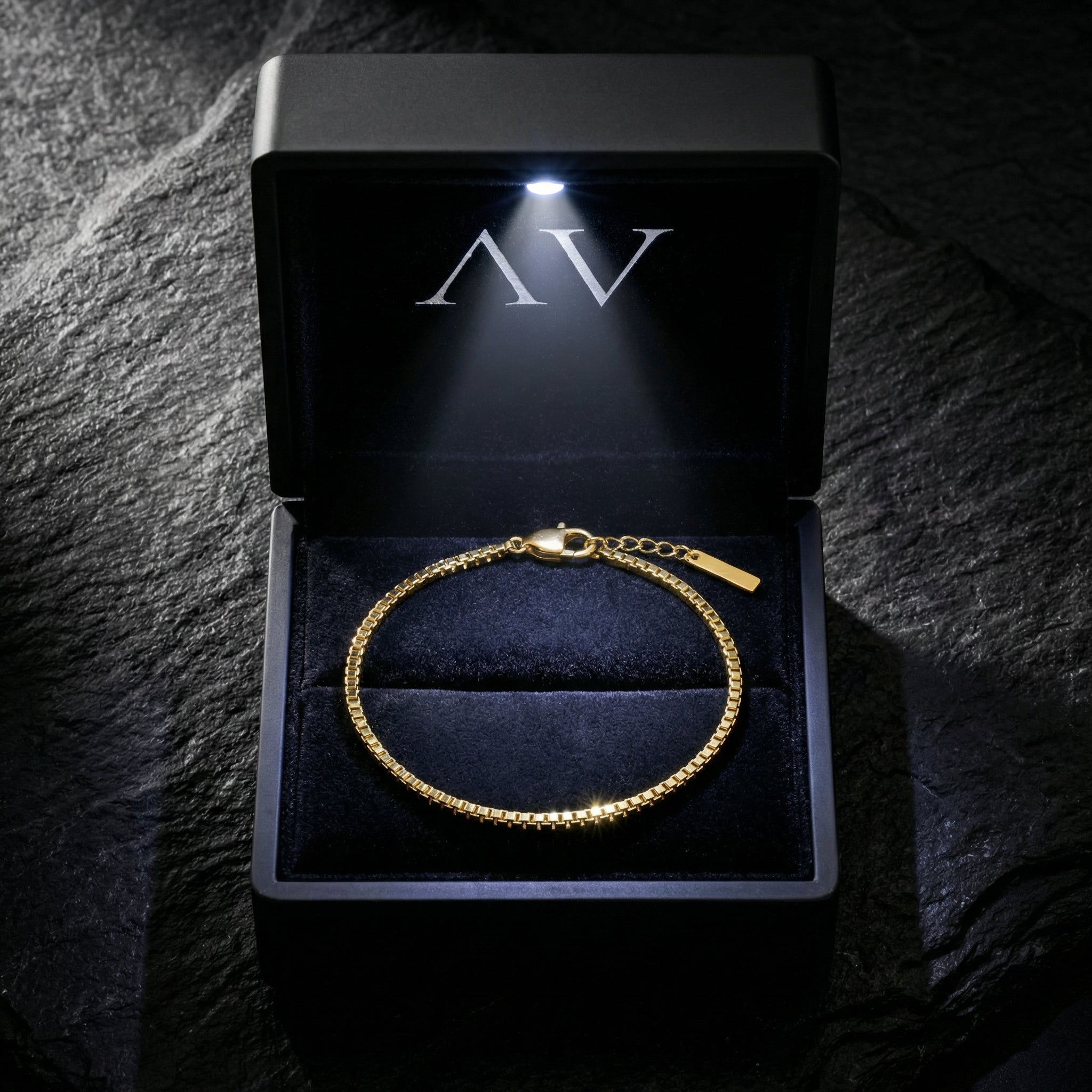 Gold stainless steel box chain bracelet presented in a black lighted jewelry box with AV branding.