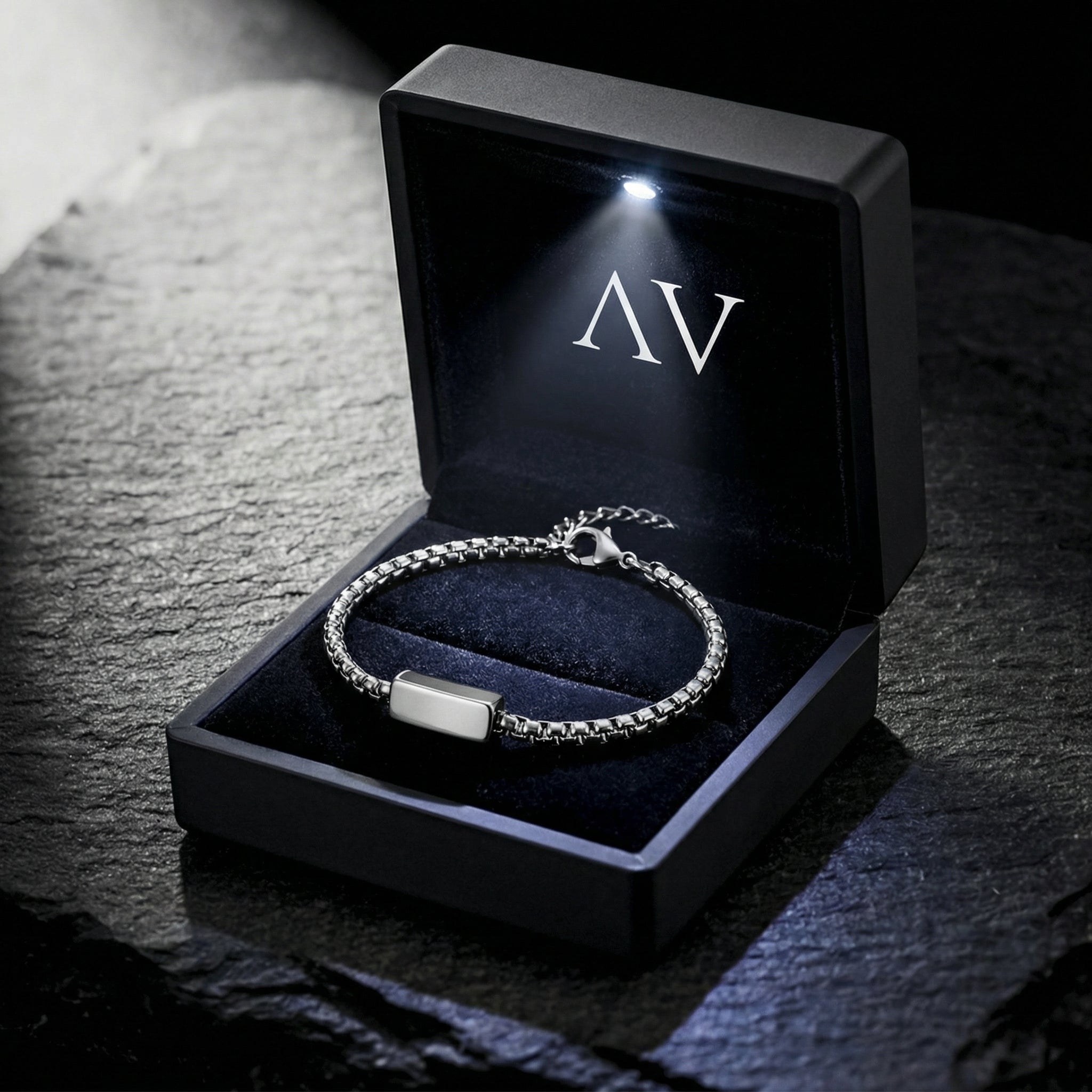 5mm silver stainless steel link ID bracelet inside a black LED-lit presentation box on a stone background.