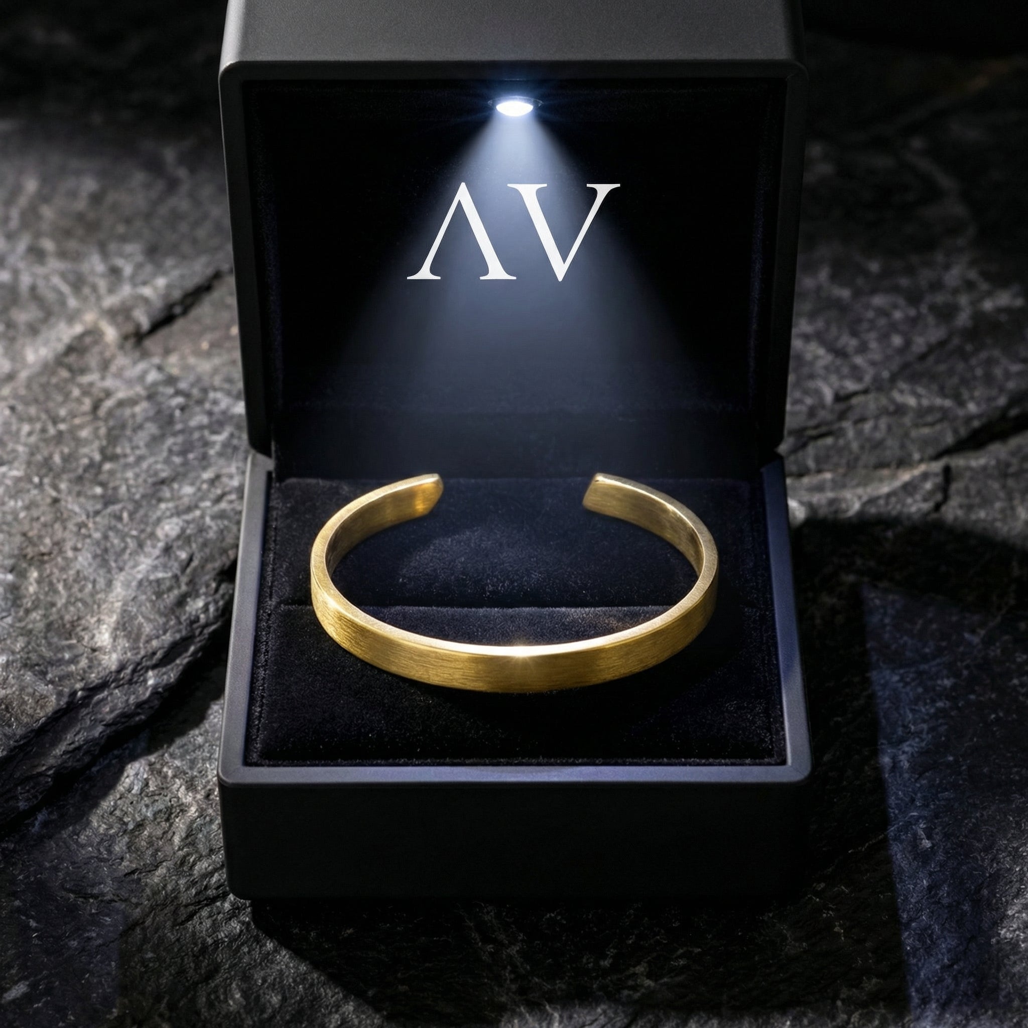 Gold stainless steel Meridian Cuff bracelet presented in a black LED-lit gift box with AV logo.