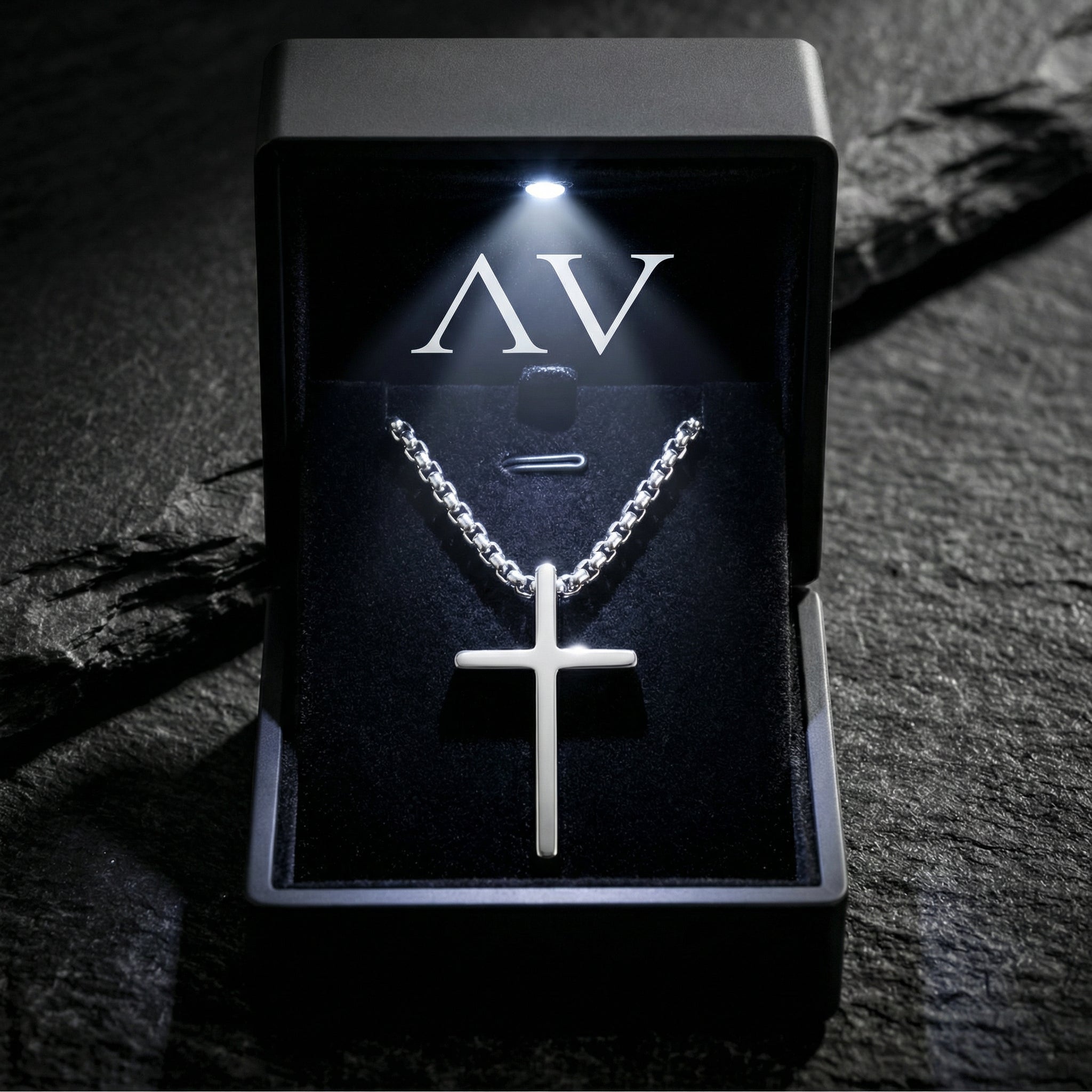 Silver stainless steel cross necklace displayed in a lighted black jewelry gift box with AV branding.