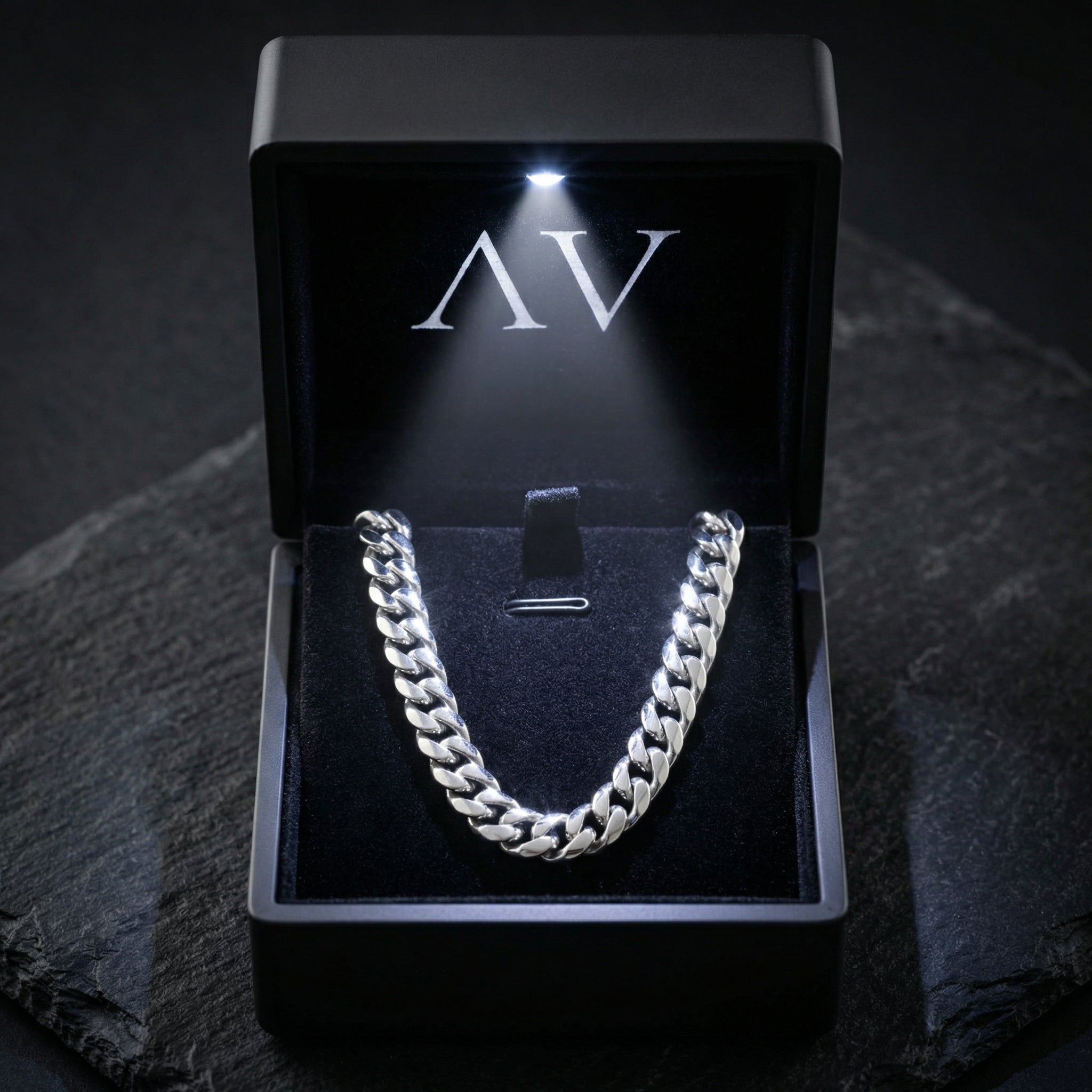 12mm silver stainless steel Cuban link chain inside a black illuminated jewelry presentation box.