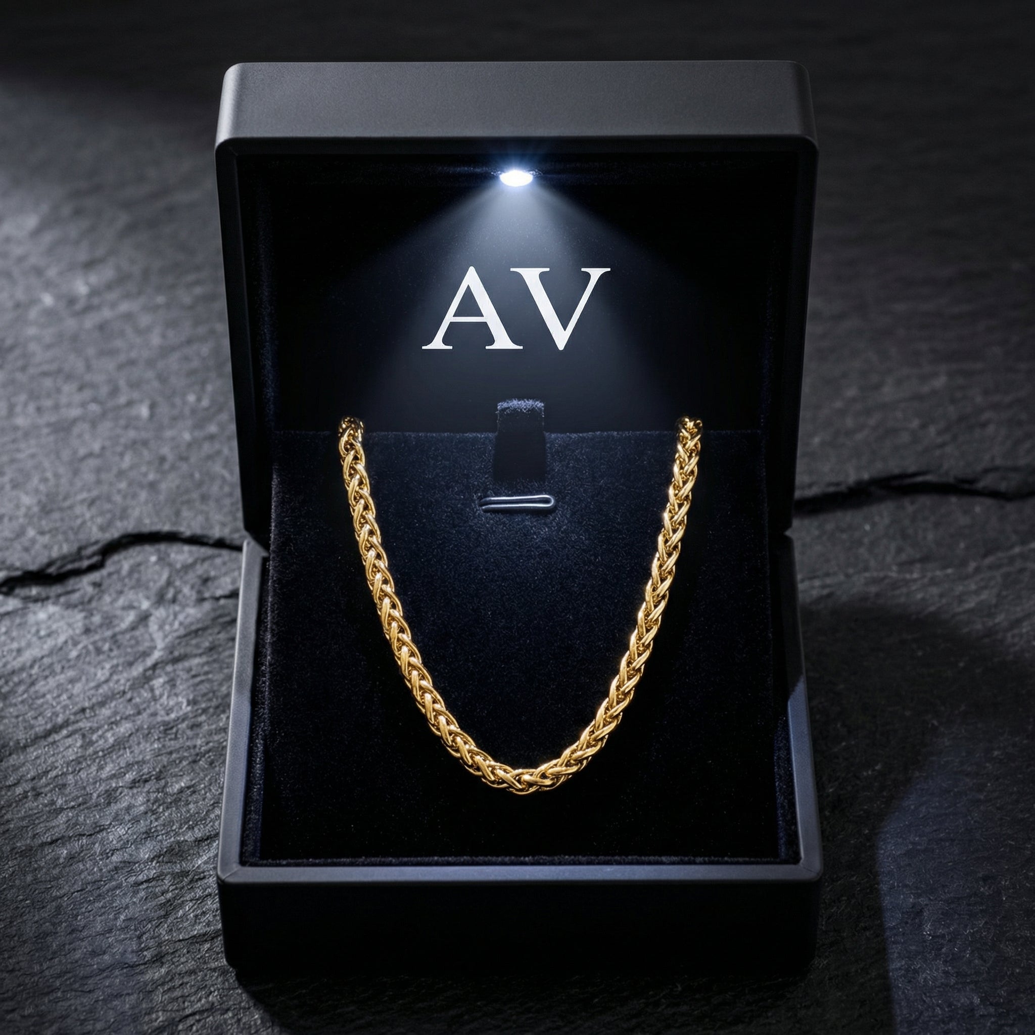 Gold stainless steel wheat chain presented in a black LED-lit jewelry box with AV logo.