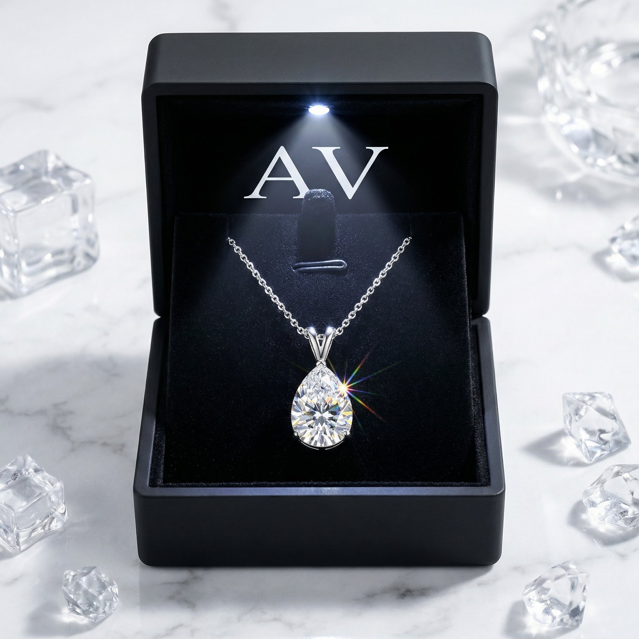 Pear-cut moissanite necklace presented in a black LED-lit gift box on a marble surface with ice accents.