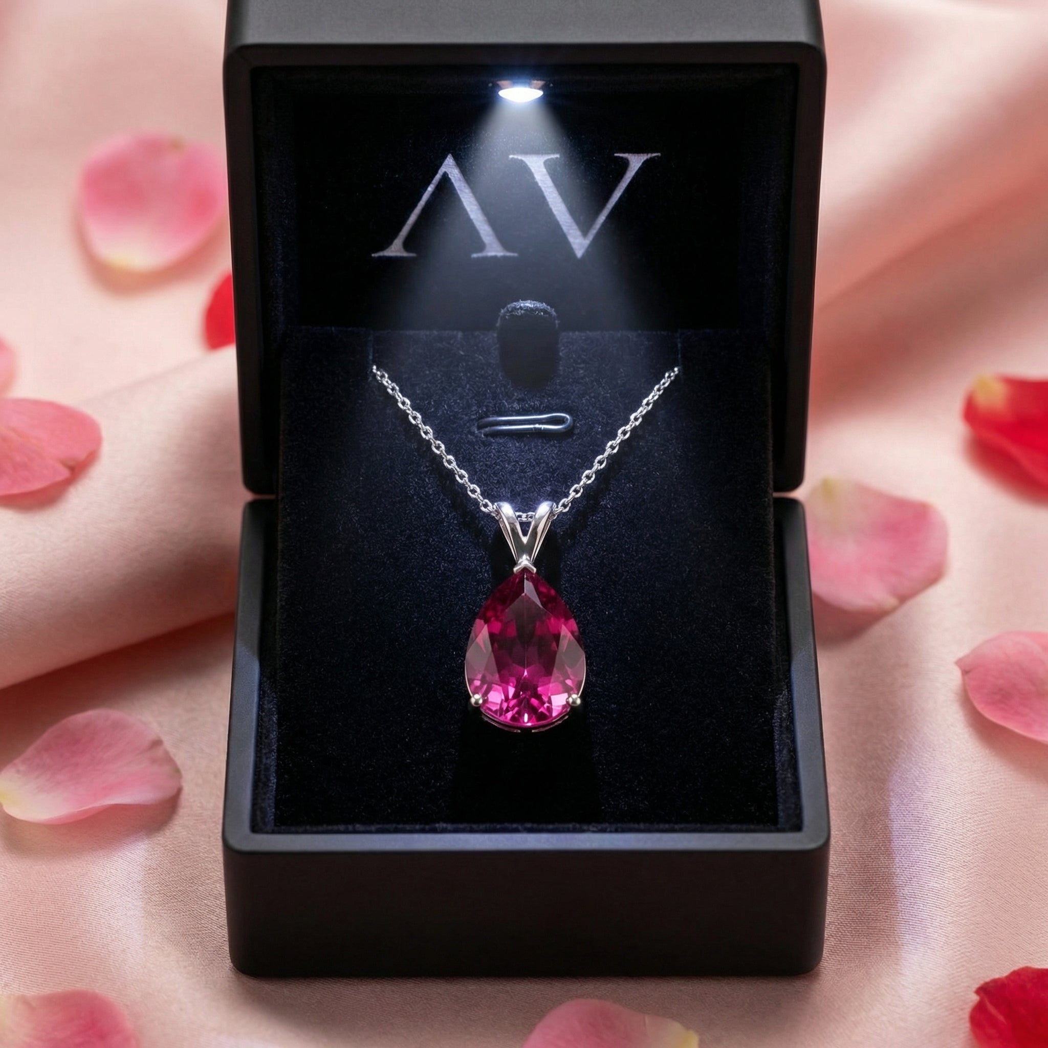 Pear-cut simulated pink tourmaline silver necklace in a black lighted gift box on pink silk.