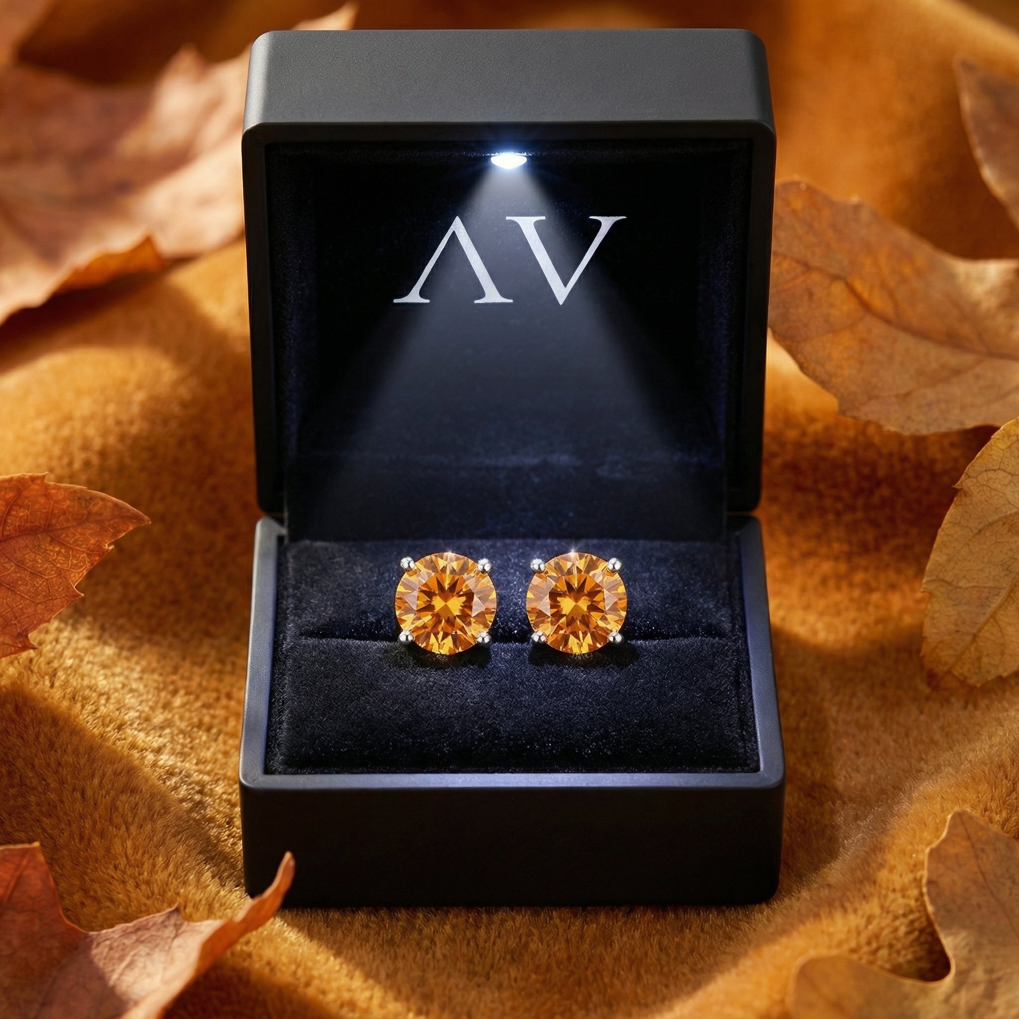 Pair of round cut simulated topaz stud earrings presented in a black LED-lit jewelry box.