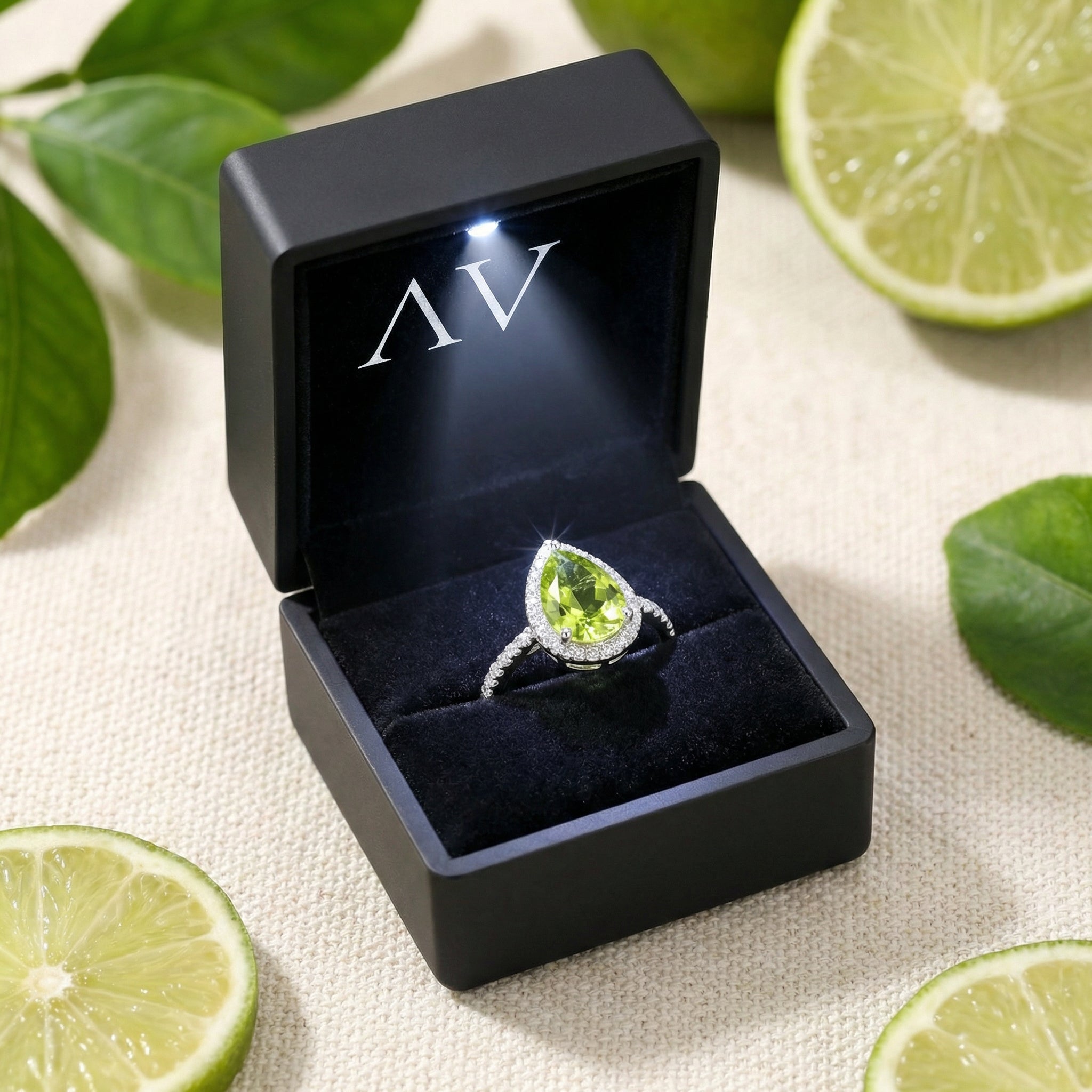 Pear-cut simulated peridot sterling silver ring inside a lighted black jewelry box with lime accents.