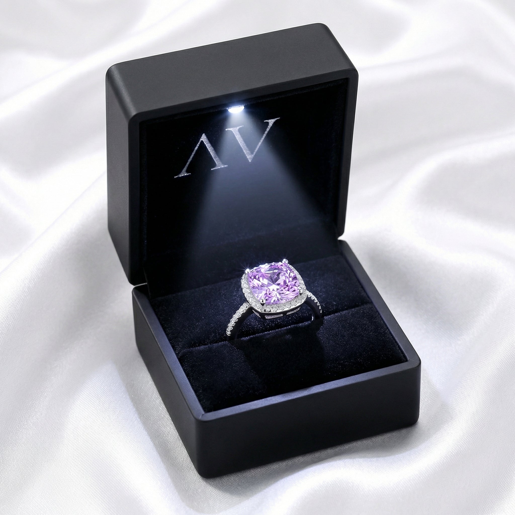 Purple simulated amethyst halo ring in a black LED-lit presentation box on white silk.