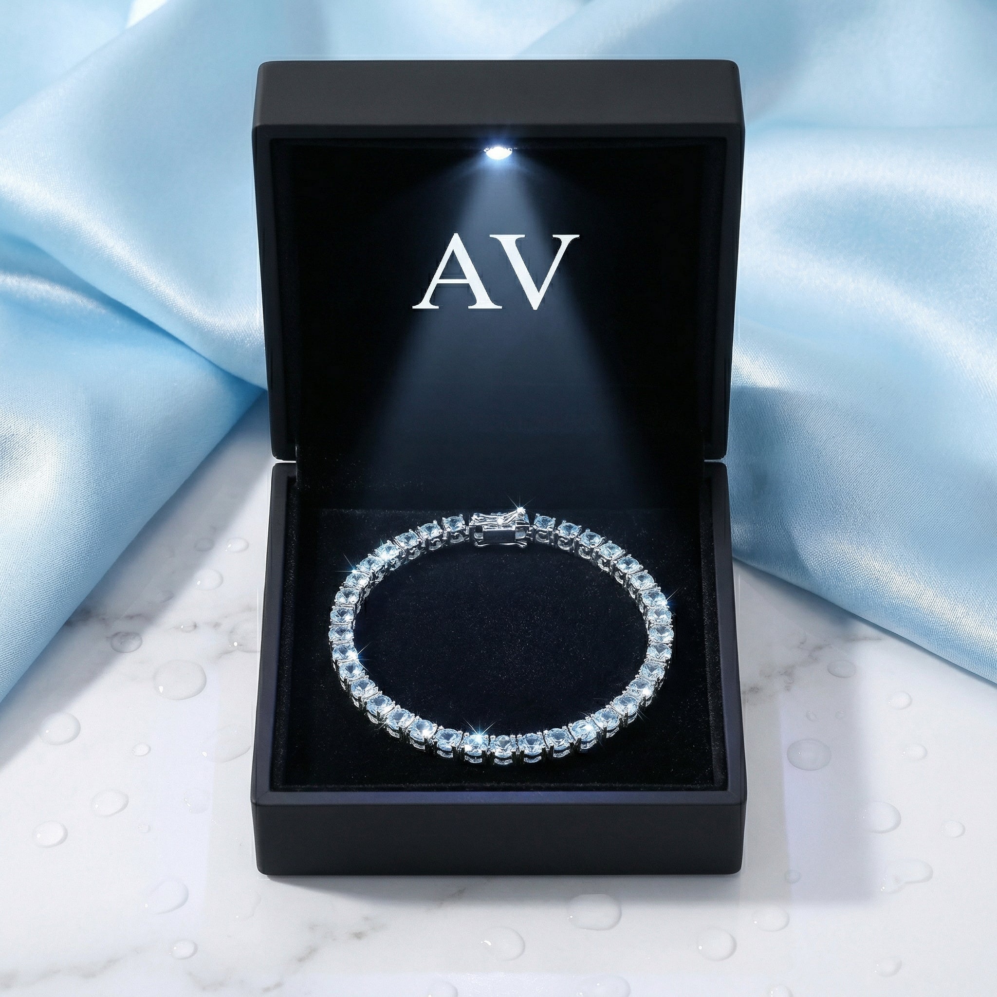 Round simulated aquamarine tennis bracelet in stainless steel inside a black LED-lit AV presentation box.