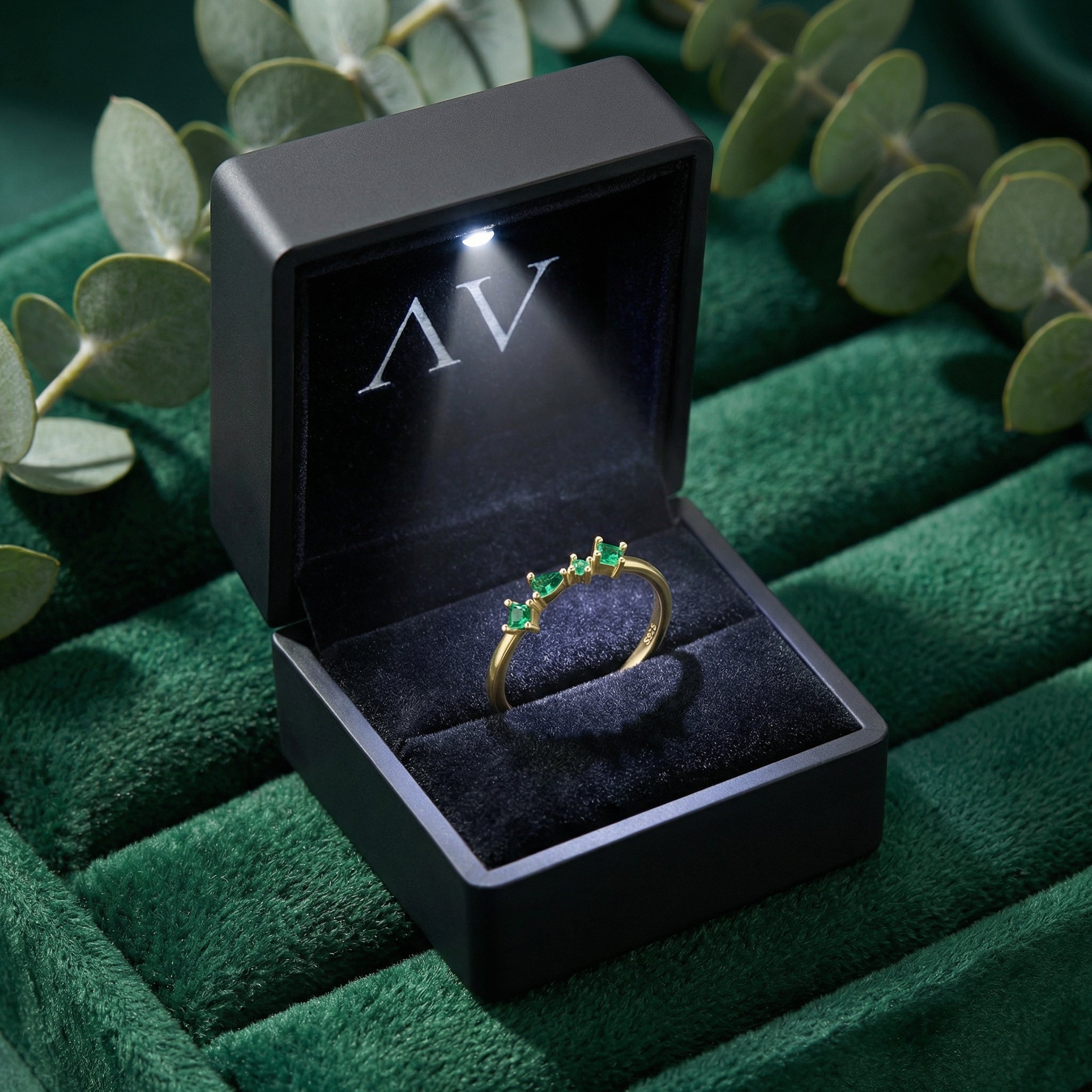 Eldora gold vermeil emerald ring presented in a black lighted jewelry box on a green velvet background.