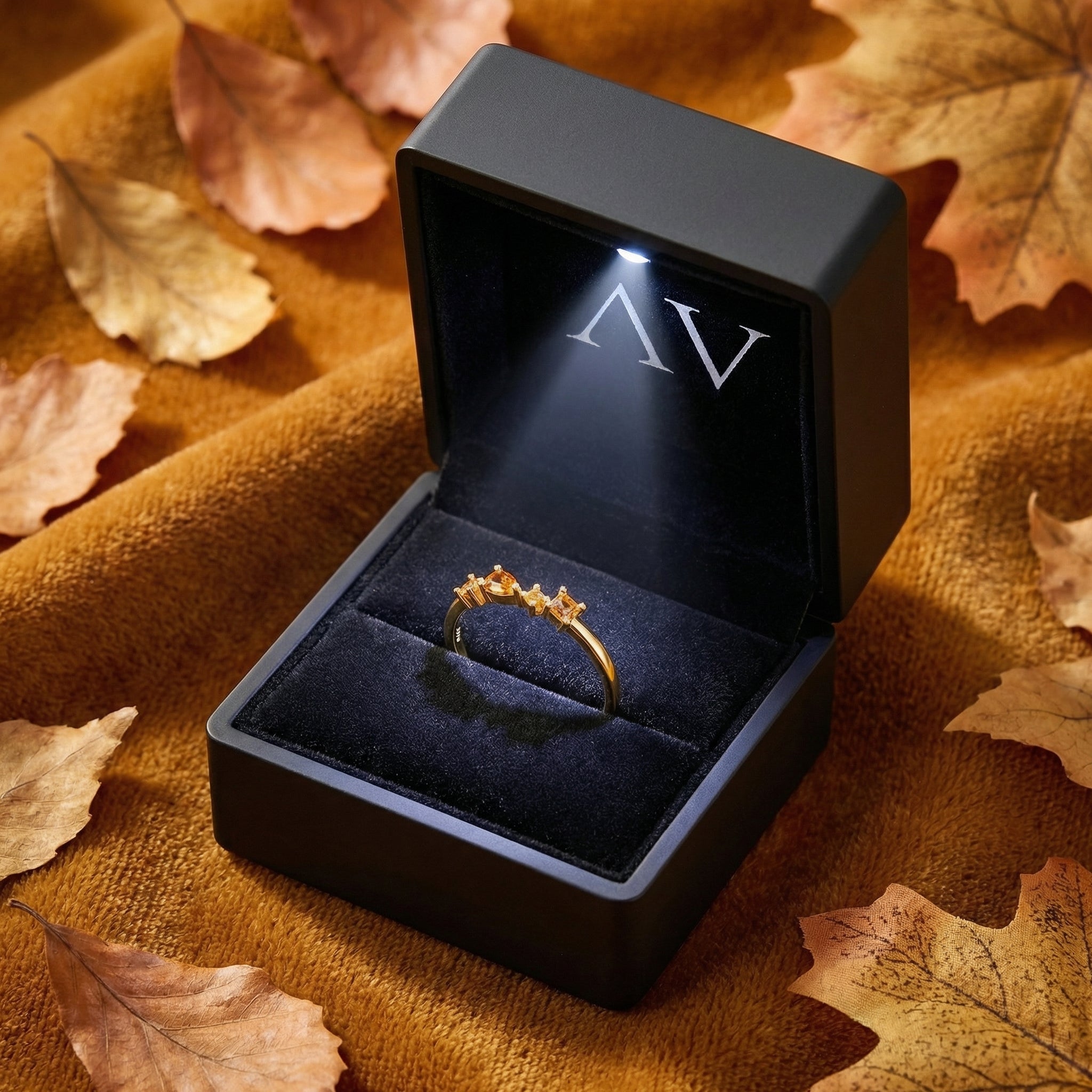 18K gold vermeil Kalisara Row ring presented in a luxury black LED-lit jewelry box with autumn leaf accents.