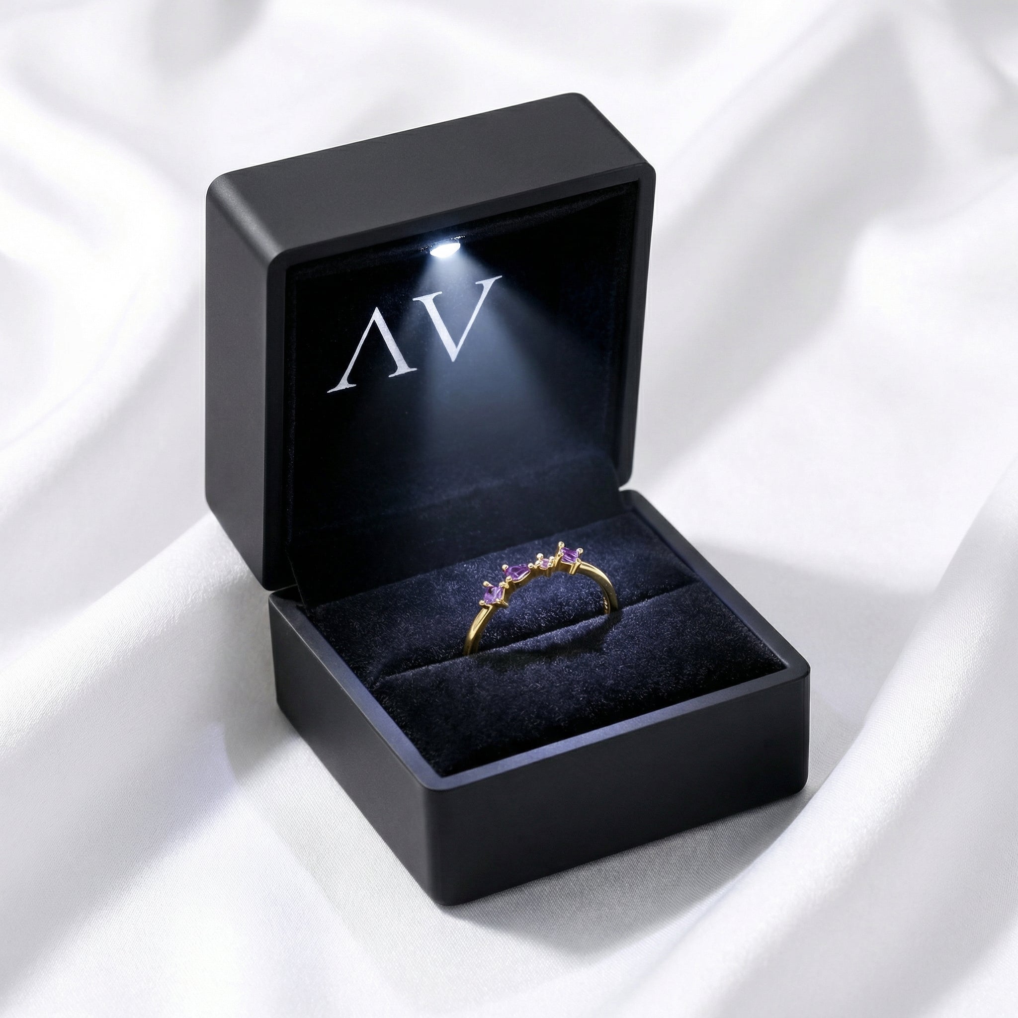 The Elisia gold vermeil ring inside a black LED-lit jewelry box on white fabric.