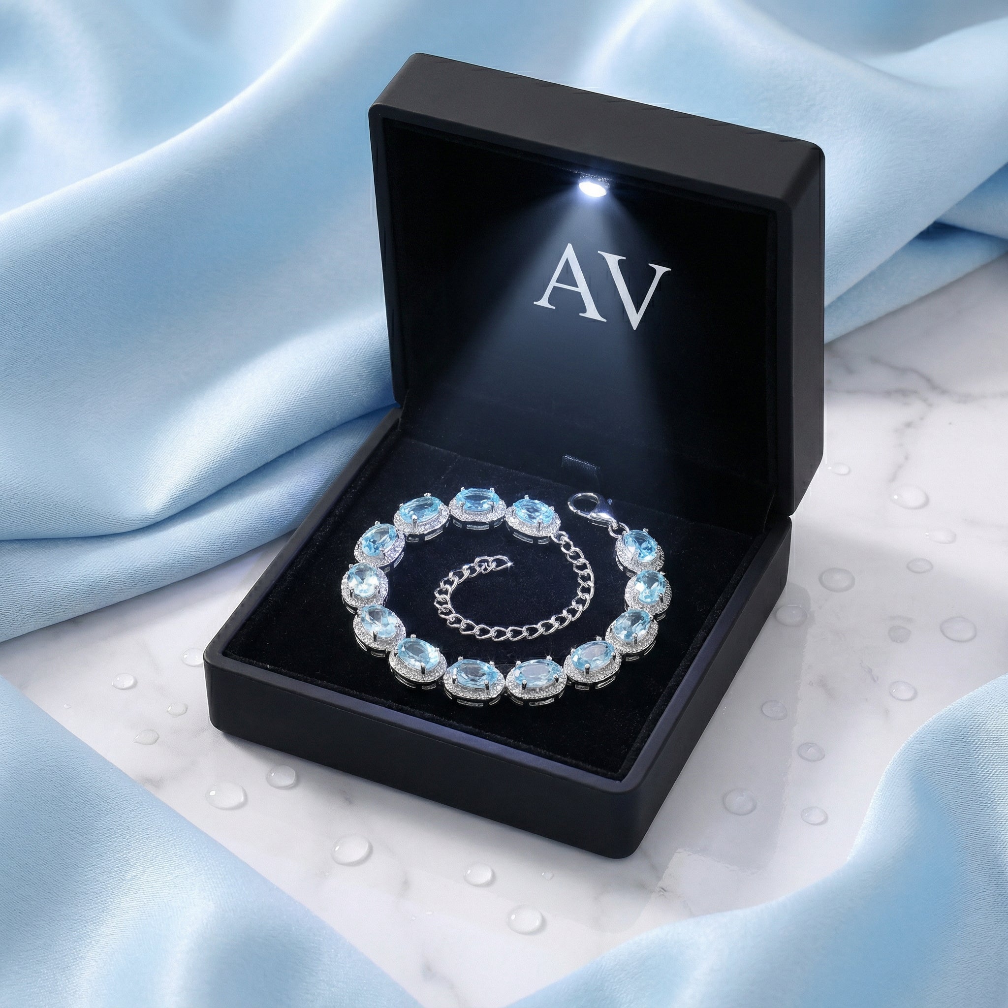 Simulated aquamarine sterling silver halo bracelet inside a black LED-lit jewelry gift box on blue silk.