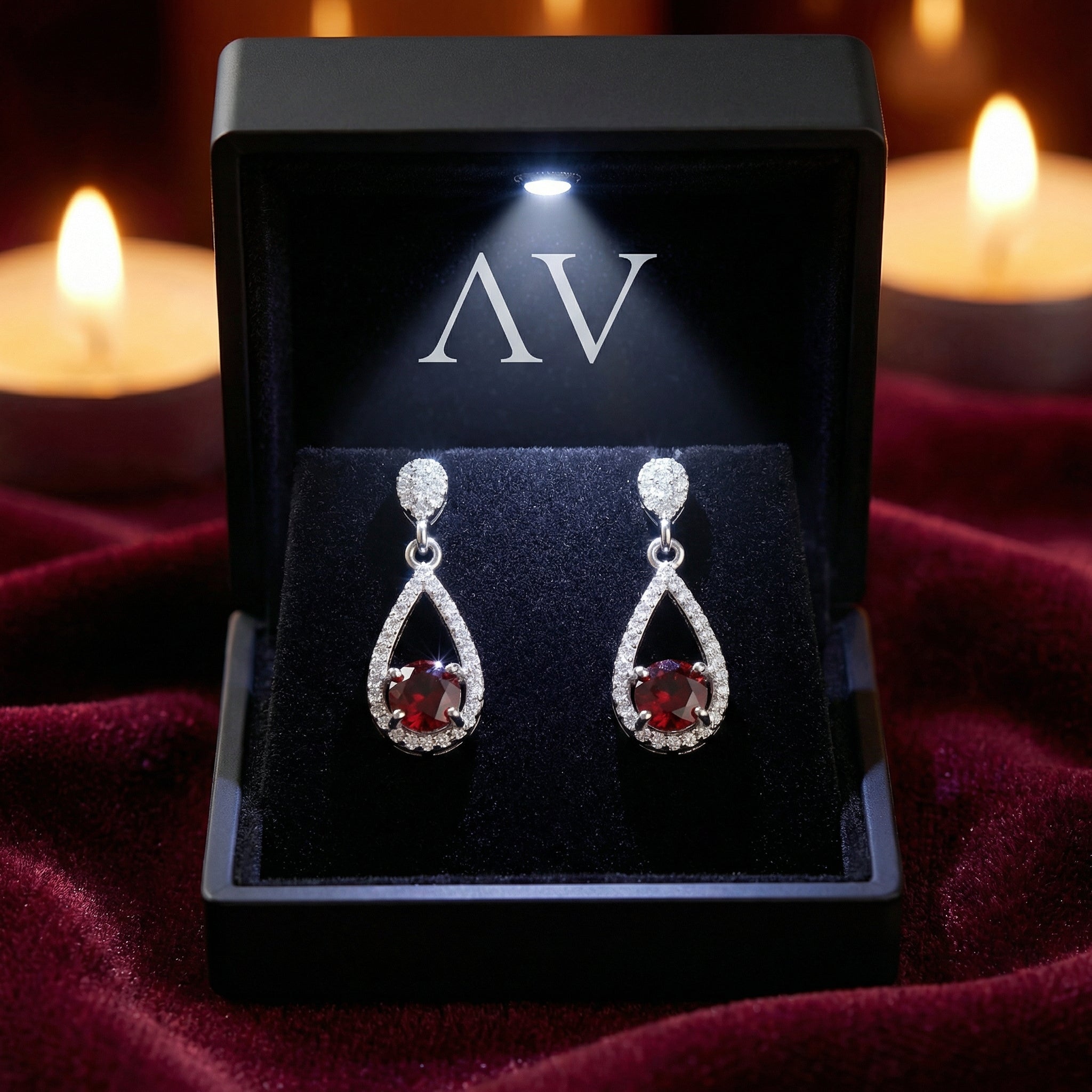 Simulated garnet sterling silver teardrop earrings in a black LED-lighted gift box on red velvet.