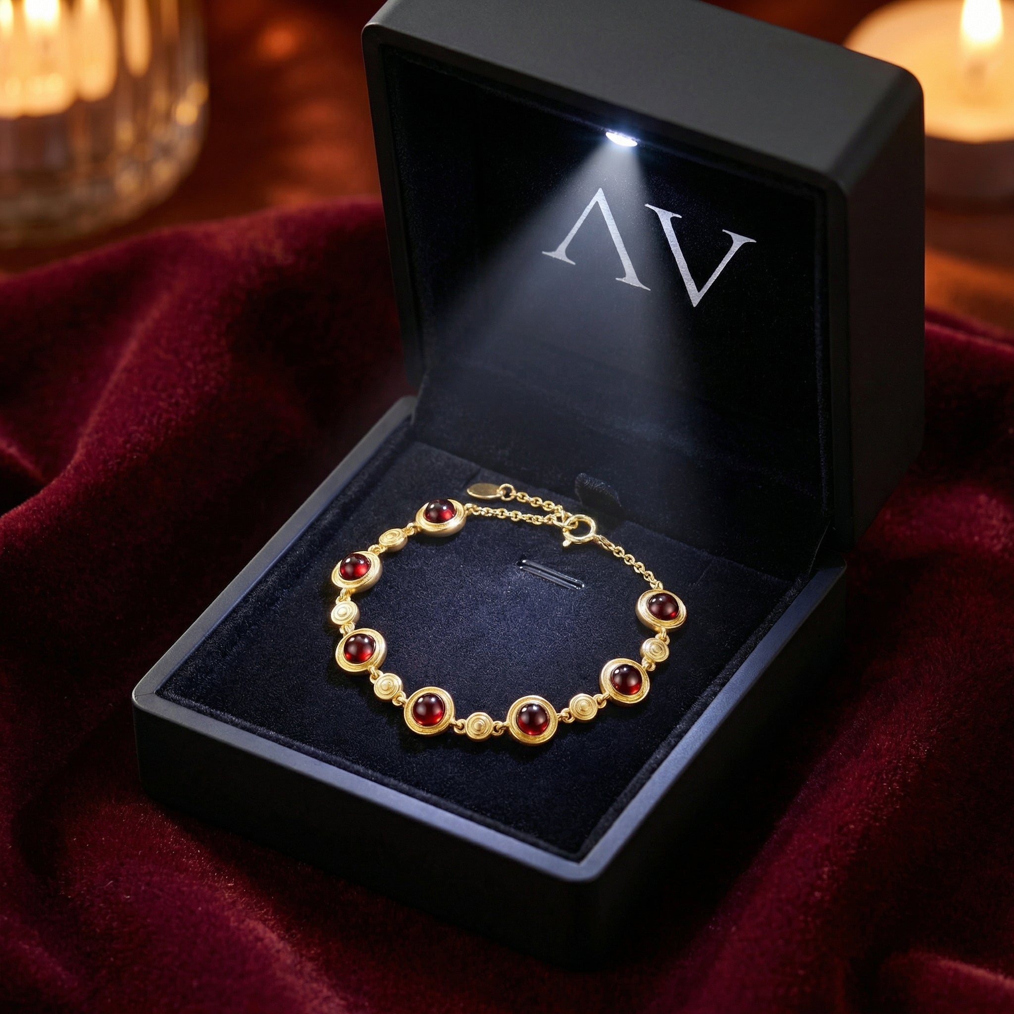 Calyssa simulated garnet station bracelet in 18K gold vermeil inside a lighted black jewelry gift box.