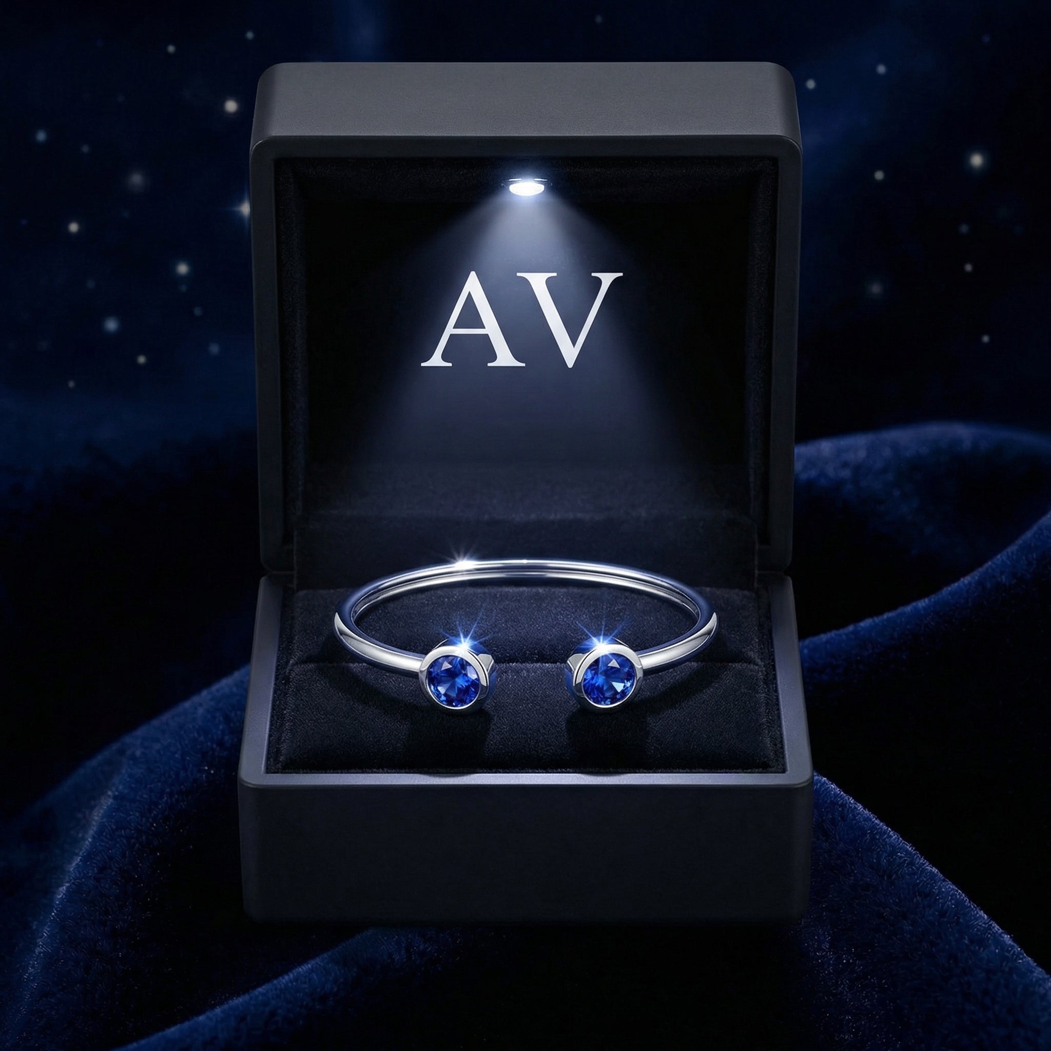 Silver stainless steel Verian bangle with blue simulated sapphires in a lighted black jewelry gift box.