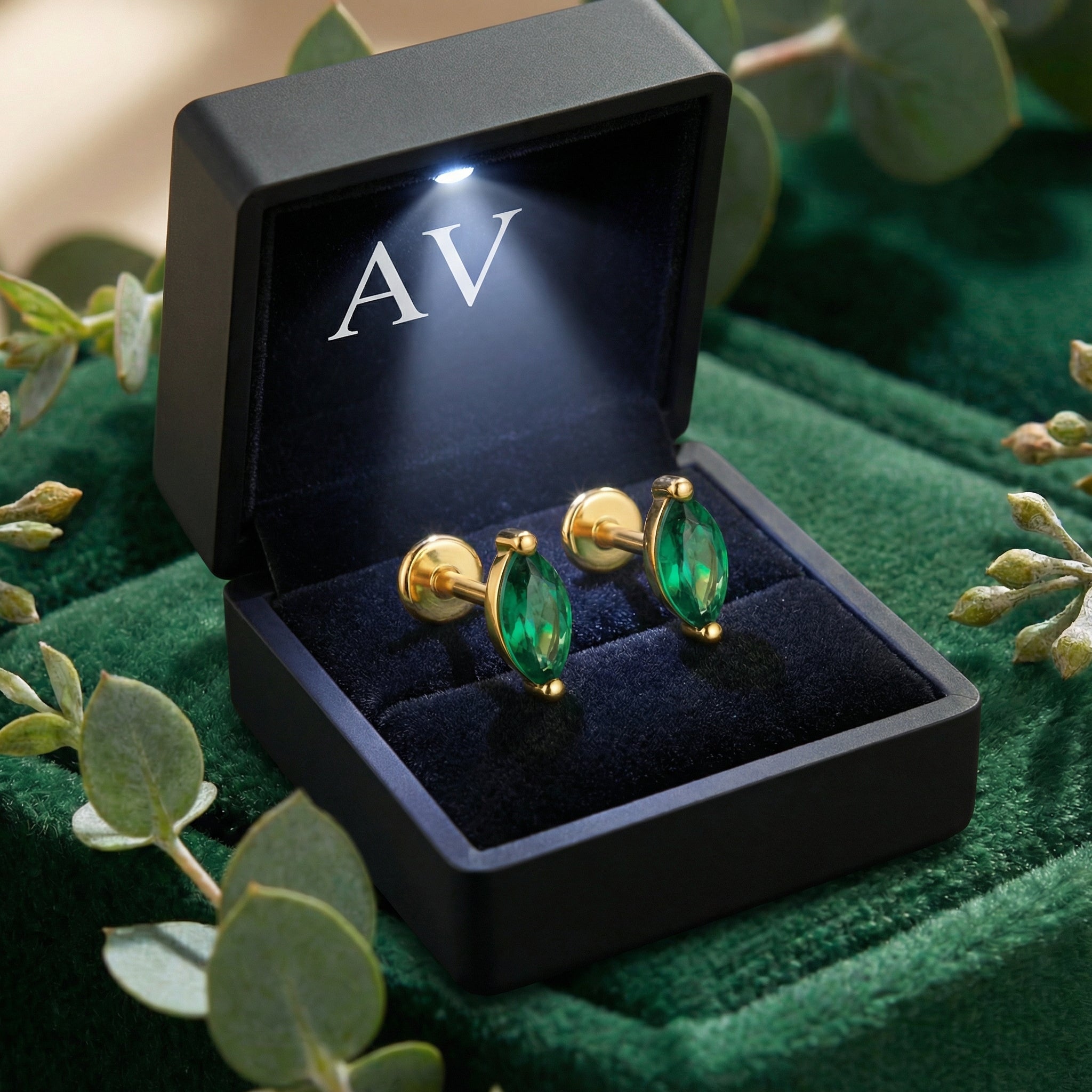 Marquise-cut simulated emerald stud earrings in 18K gold vermeil inside a lighted black jewelry gift box.