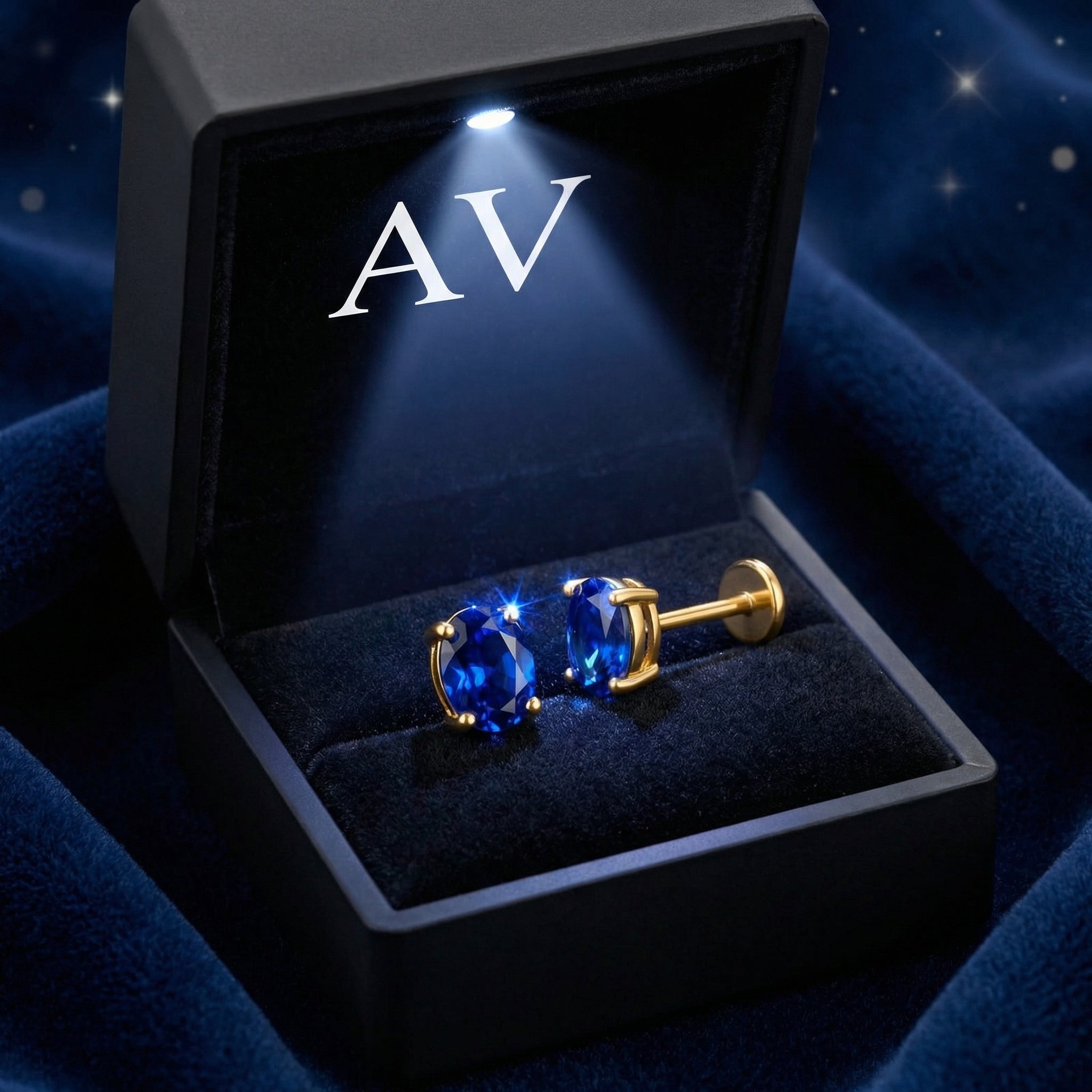 Oval simulated sapphire stud earrings in 18K gold vermeil inside a lighted black jewelry gift box.