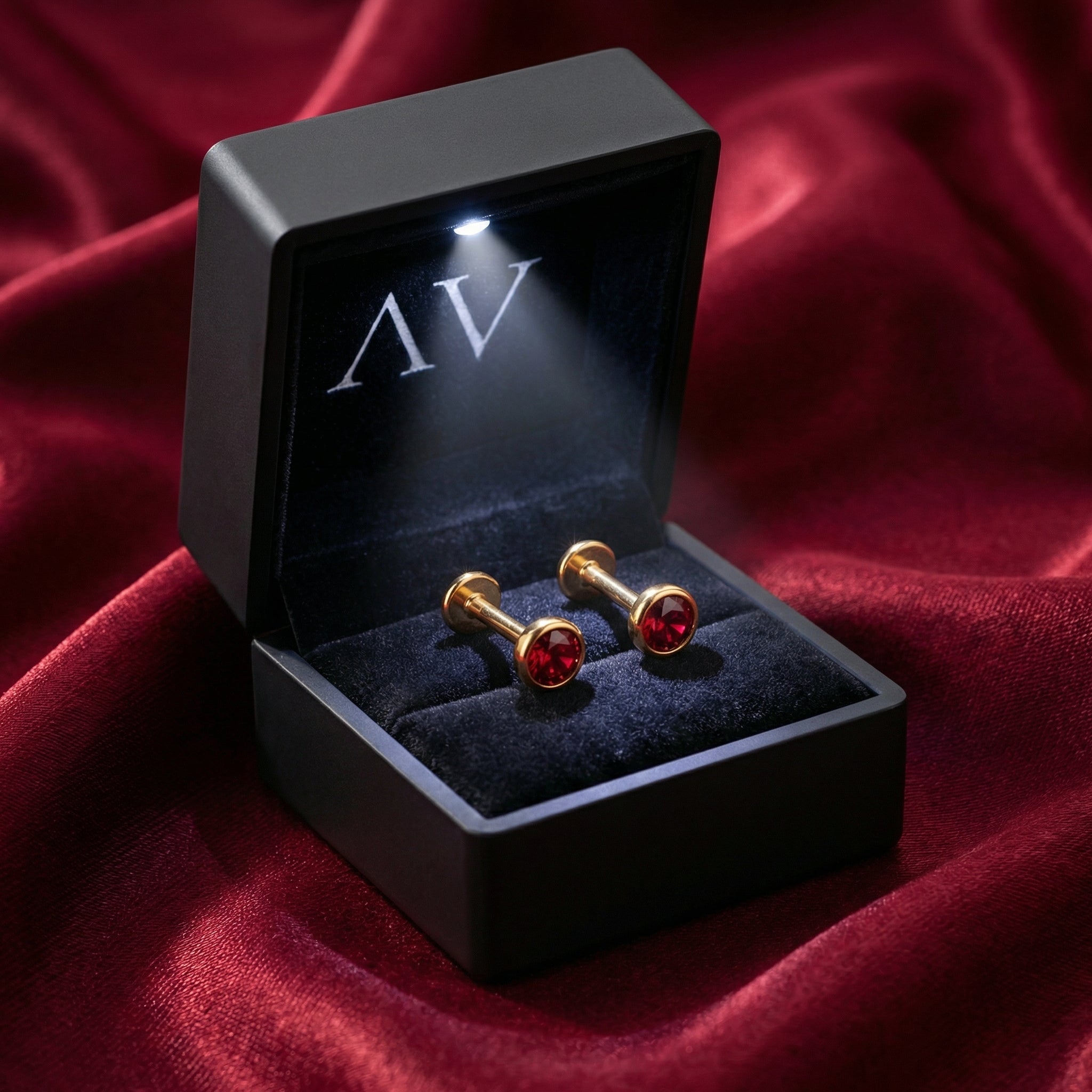 Gold vermeil simulated ruby stud earrings inside a black LED-lighted jewelry box on red satin.