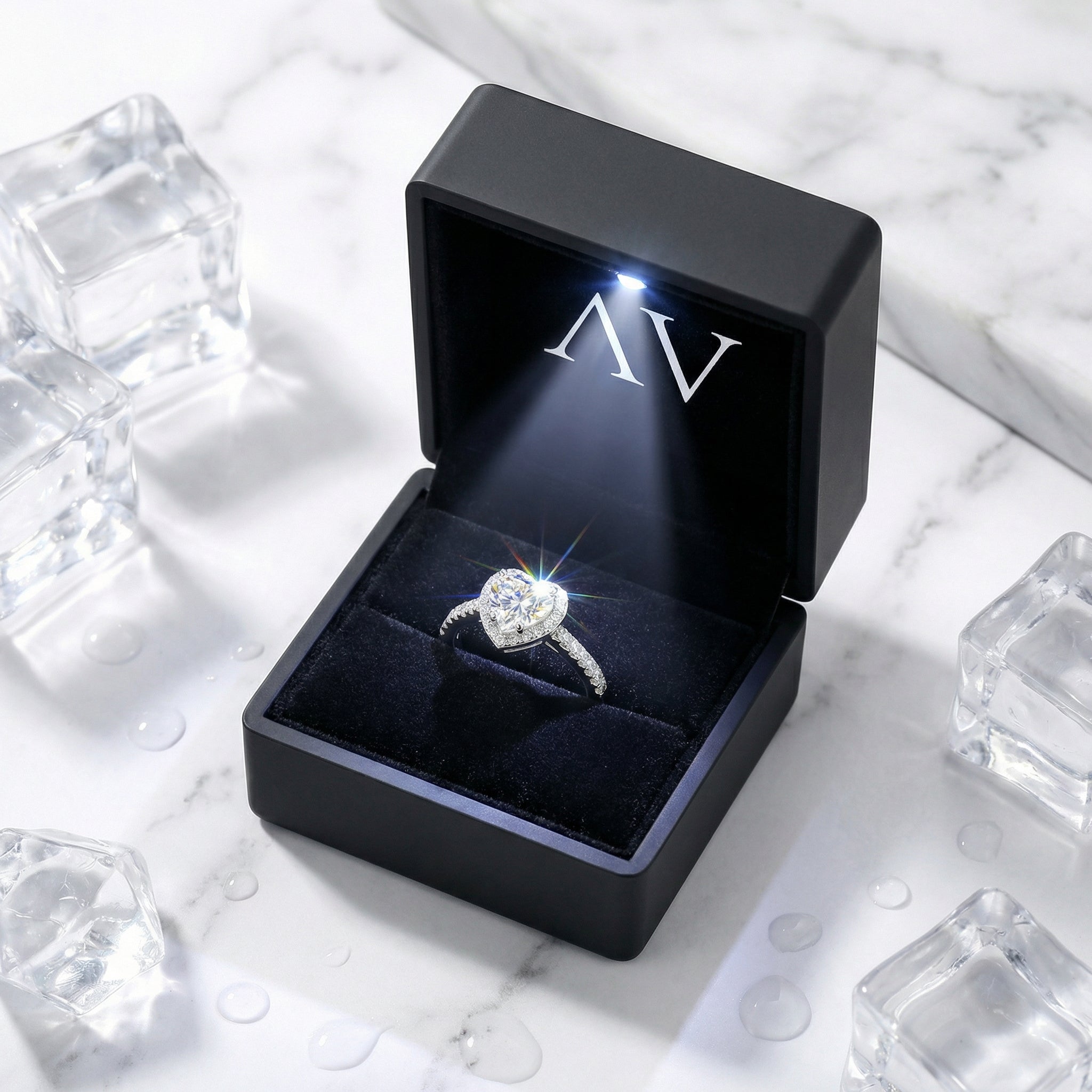 Heart-shaped sterling silver ring in a black LED-lit jewelry box on a marble and ice background.