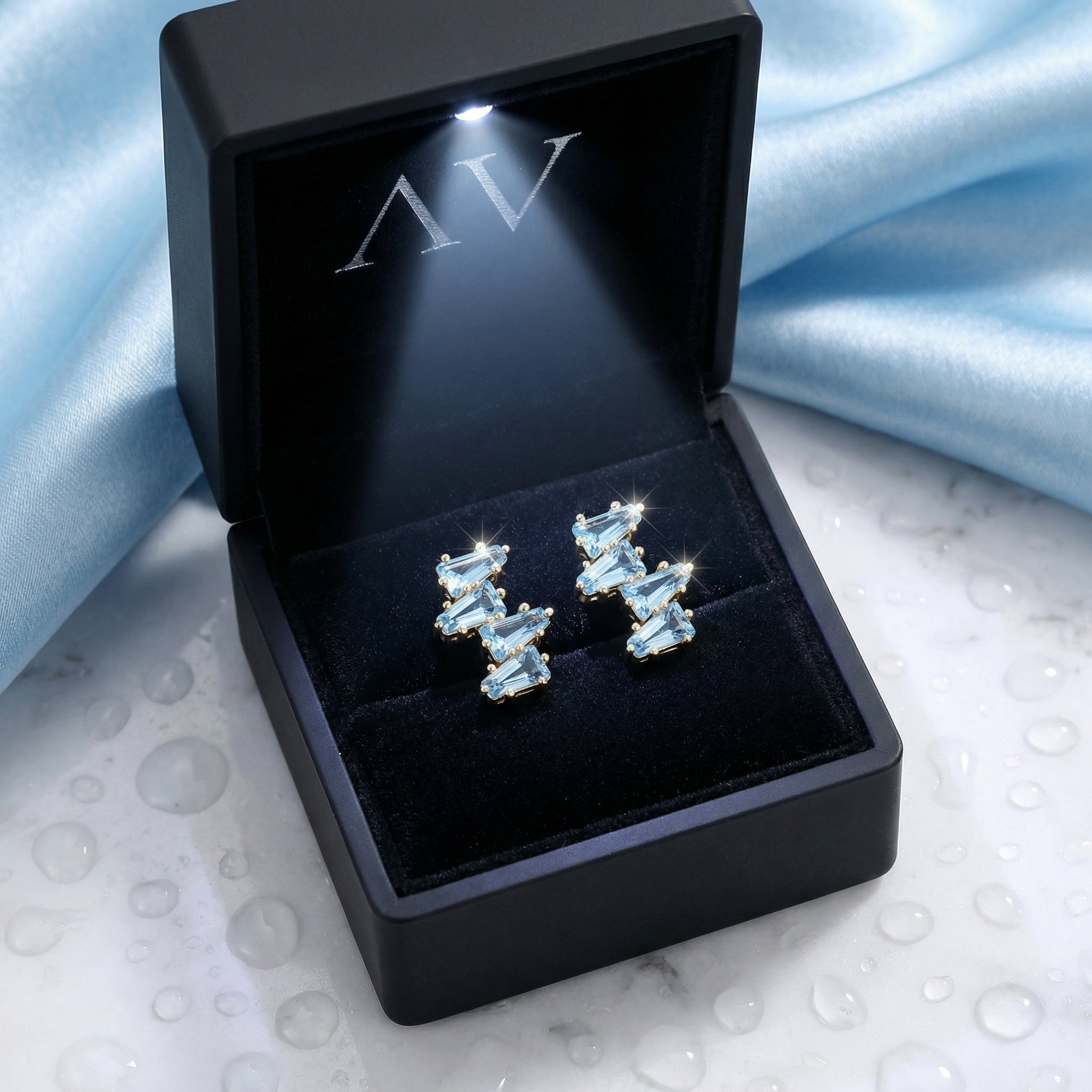 Lyraea Cluster 18K gold vermeil and simulated aquamarine earrings in a lighted black jewelry presentation box.
