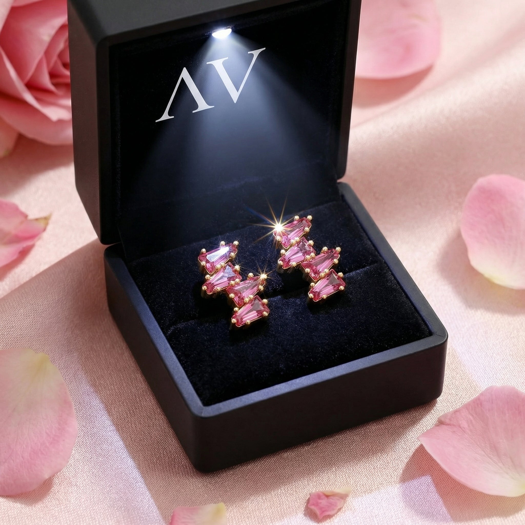 Thalissa Cascade pink tourmaline gold earrings displayed in a black LED-lighted gift box with rose petals.