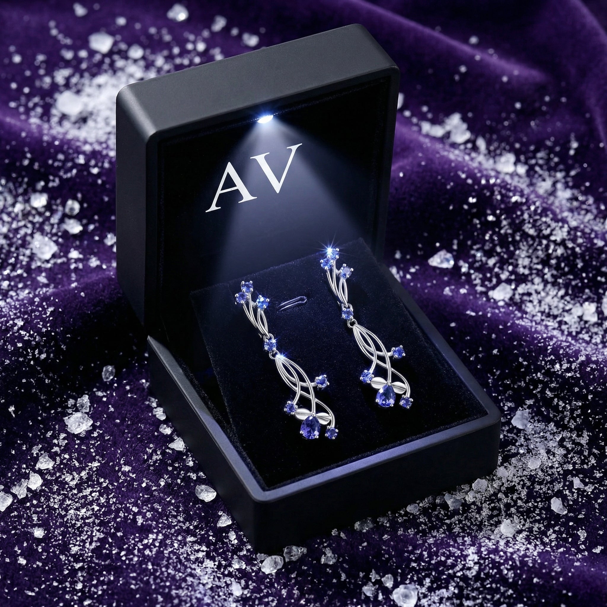 Thalinea sterling silver drop earrings with simulated tanzanite in a black LED-lit AV branded presentation box.