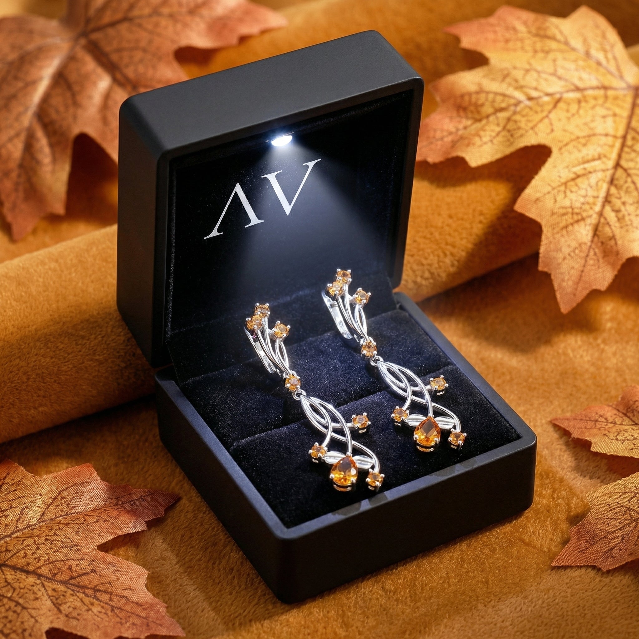 Sterling silver simulated topaz vine drop earrings in a black LED-lit jewelry box with autumn leaves.