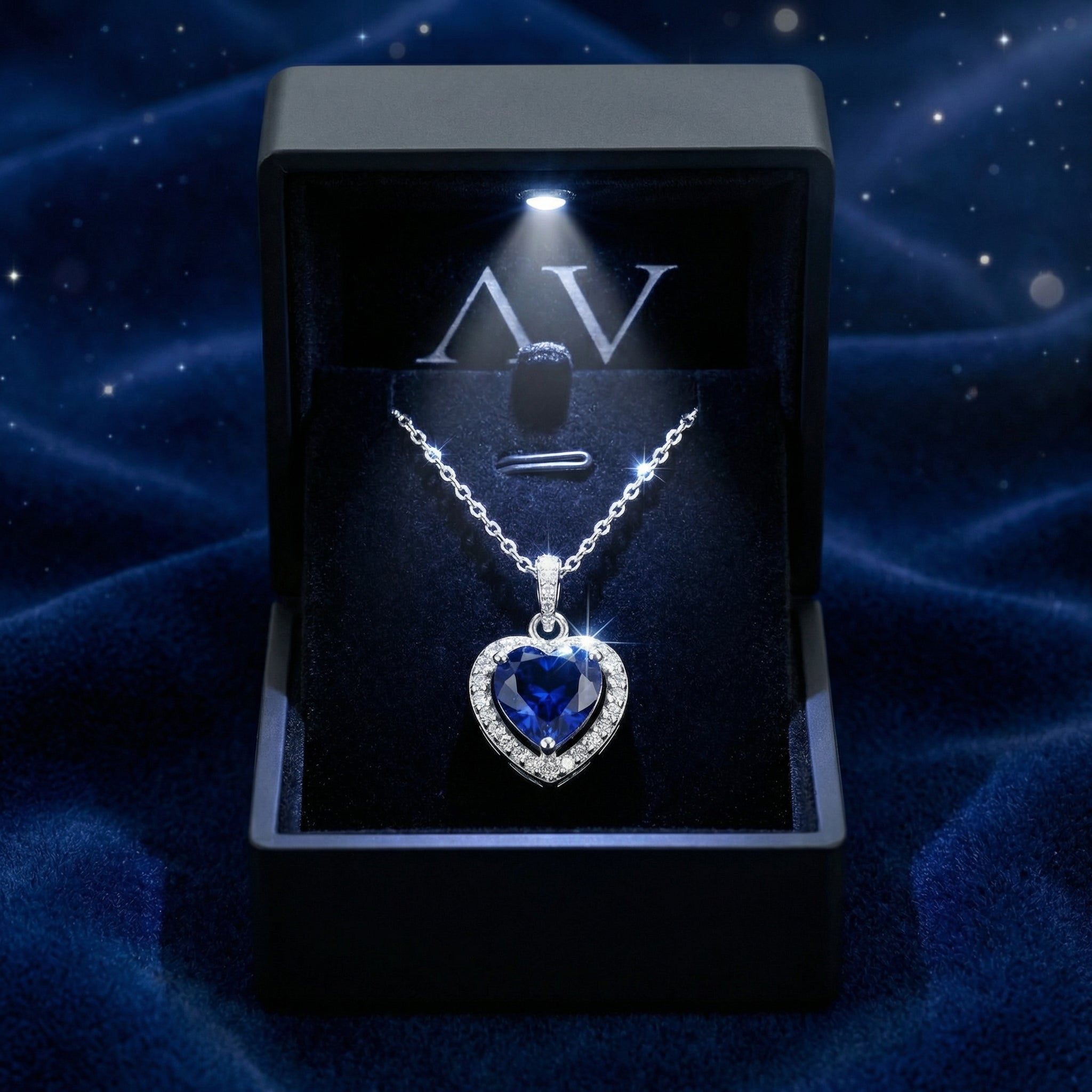 Heart-shaped simulated sapphire sterling silver necklace in a luxury black LED-lit gift box on blue fabric.