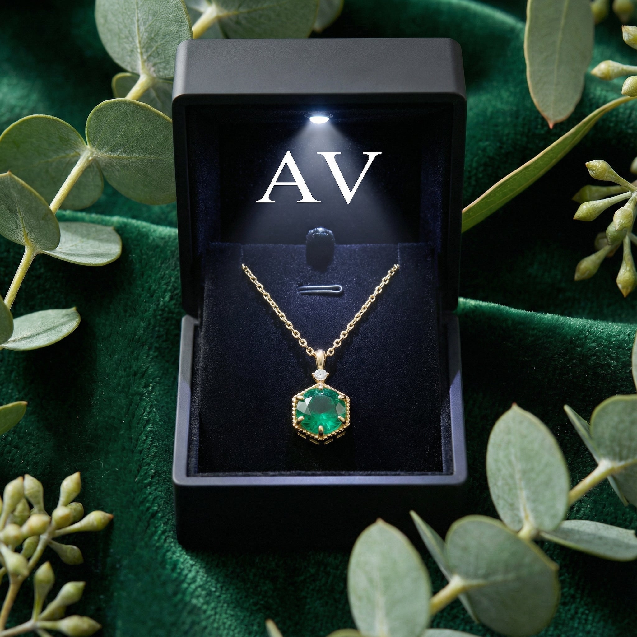 Round simulated emerald necklace in a black LED-lighted jewelry box on green velvet.