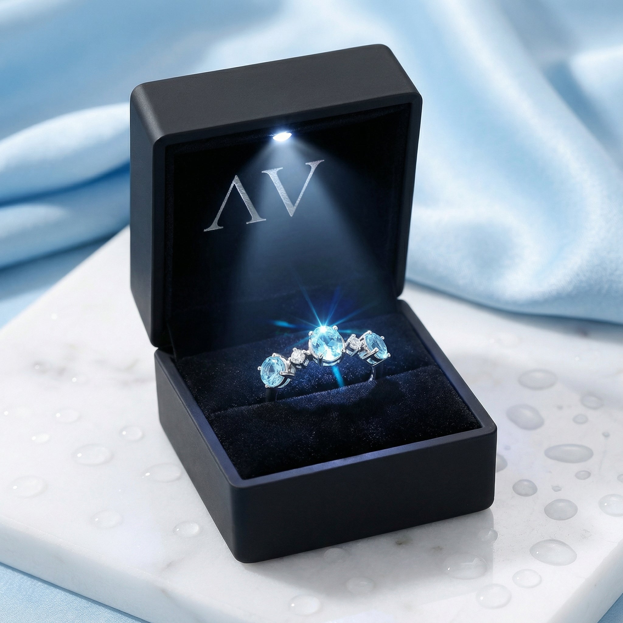 Maris bypass ring in S925 sterling silver with simulated aquamarines in a lighted black jewelry gift box.