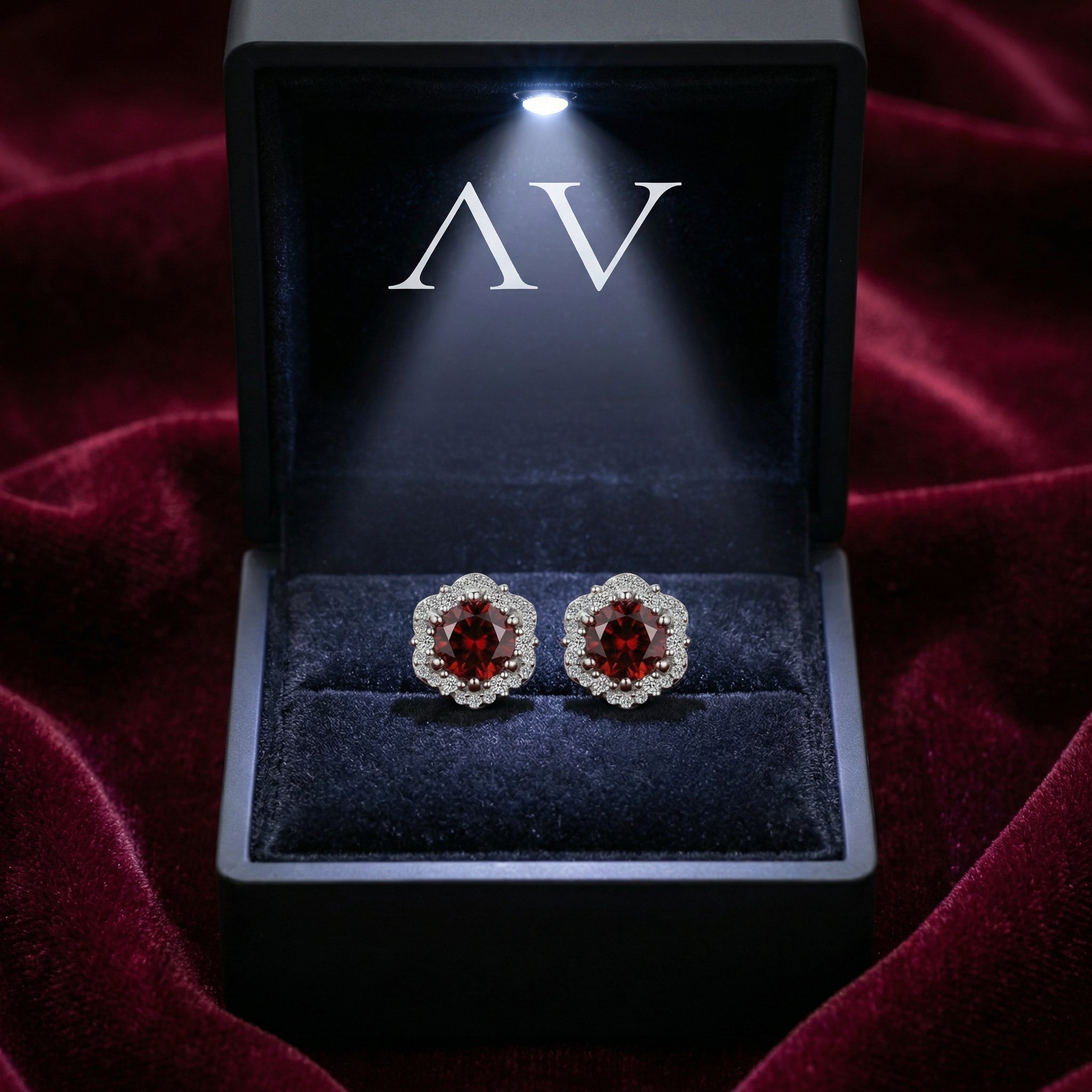 Sterling silver round simulated garnet halo stud earrings presented in a lighted black jewelry gift box.