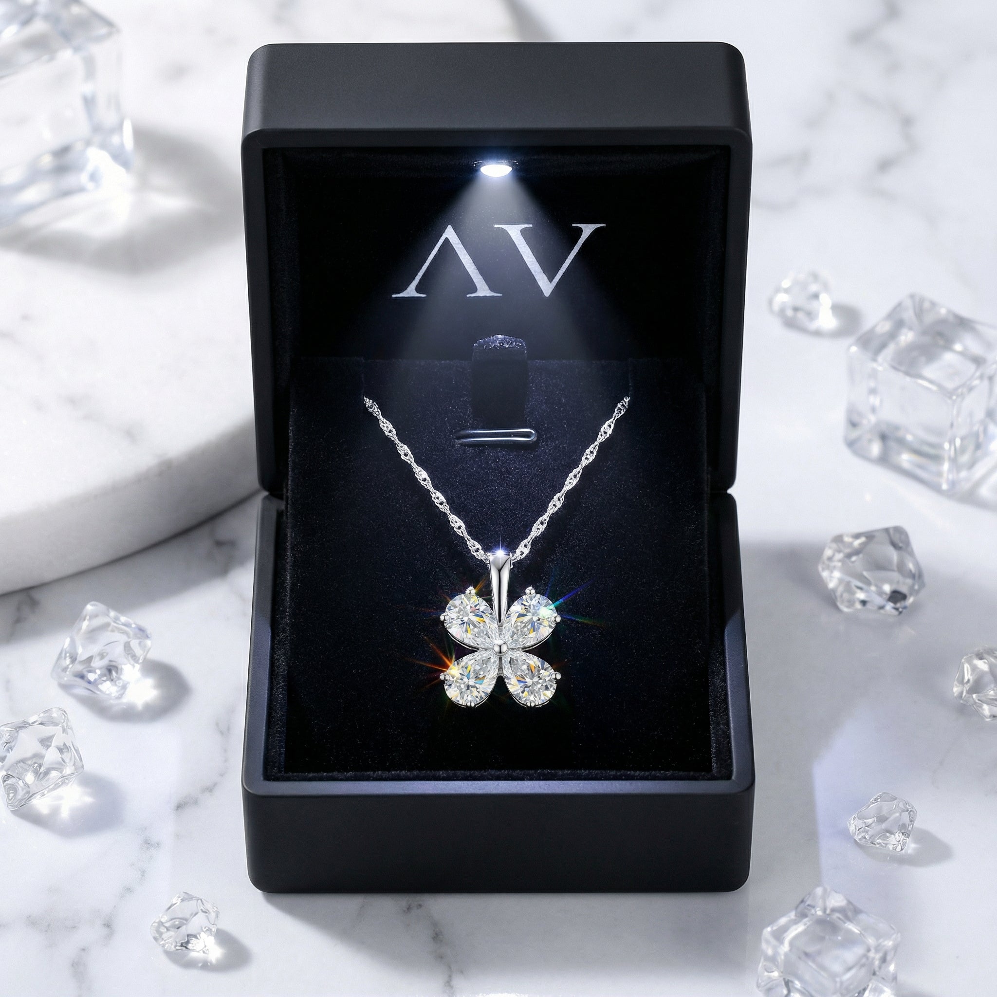 Sterling silver clover necklace presented in a premium black LED-lit jewelry gift box with crystal props.