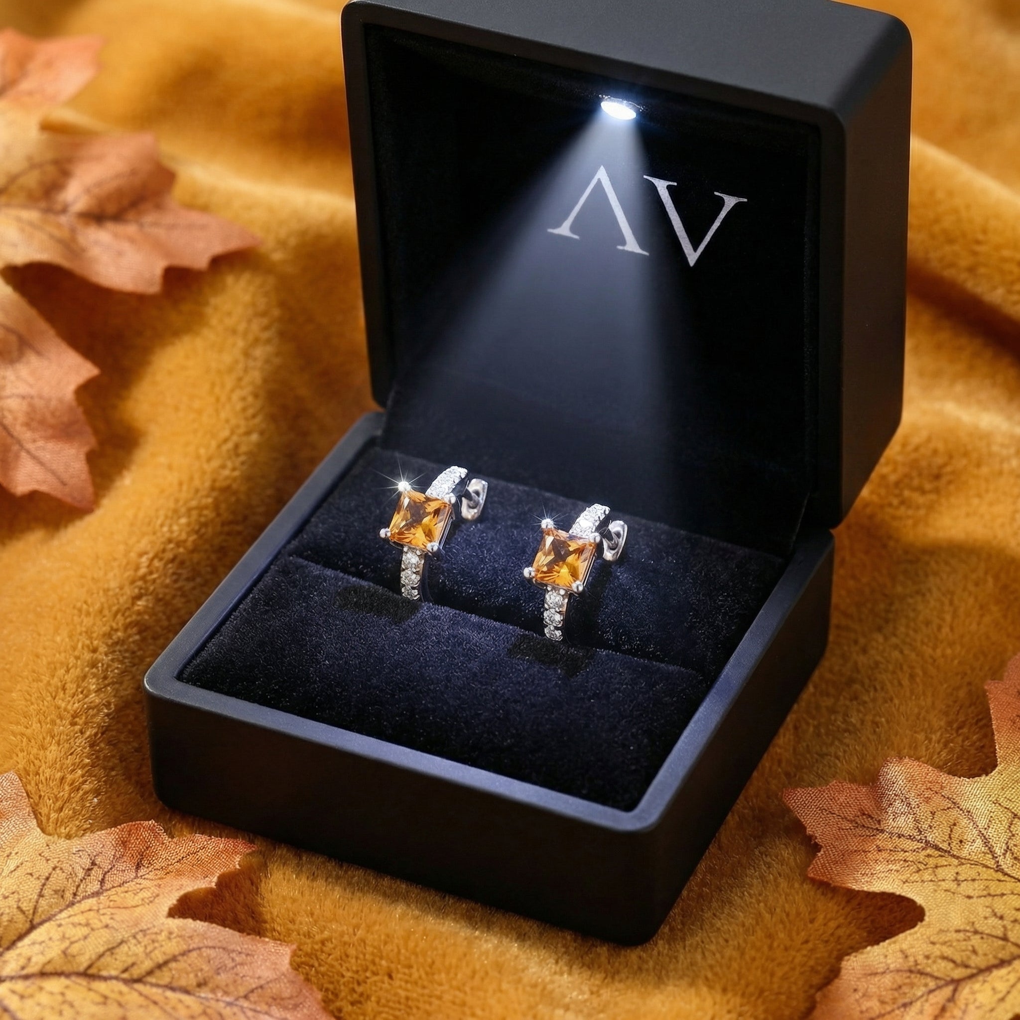 Sterling silver orange topaz huggie earrings inside a black LED-lit jewelry presentation box.