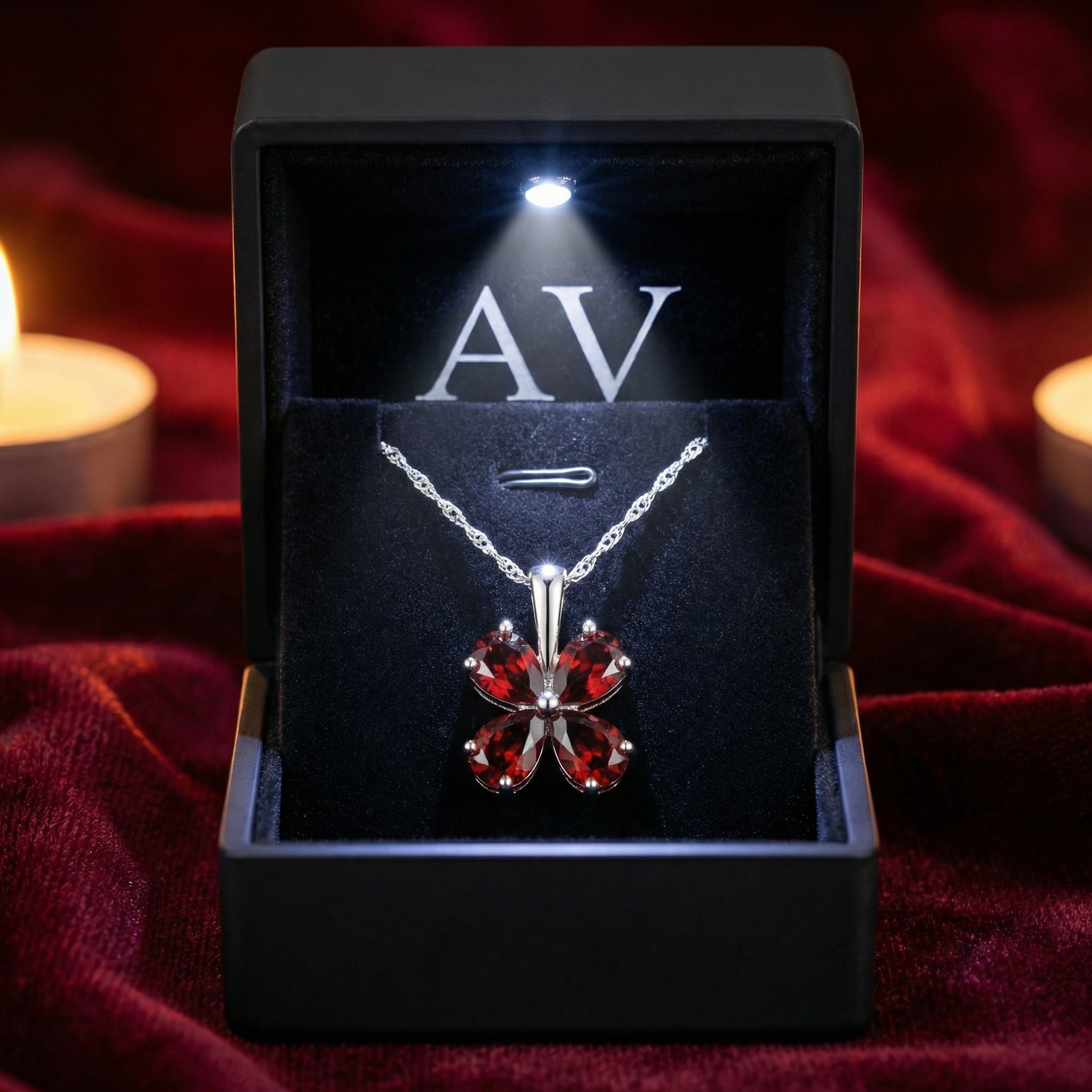 Sterling silver clover necklace with red simulated garnets inside a premium lighted black jewelry box.