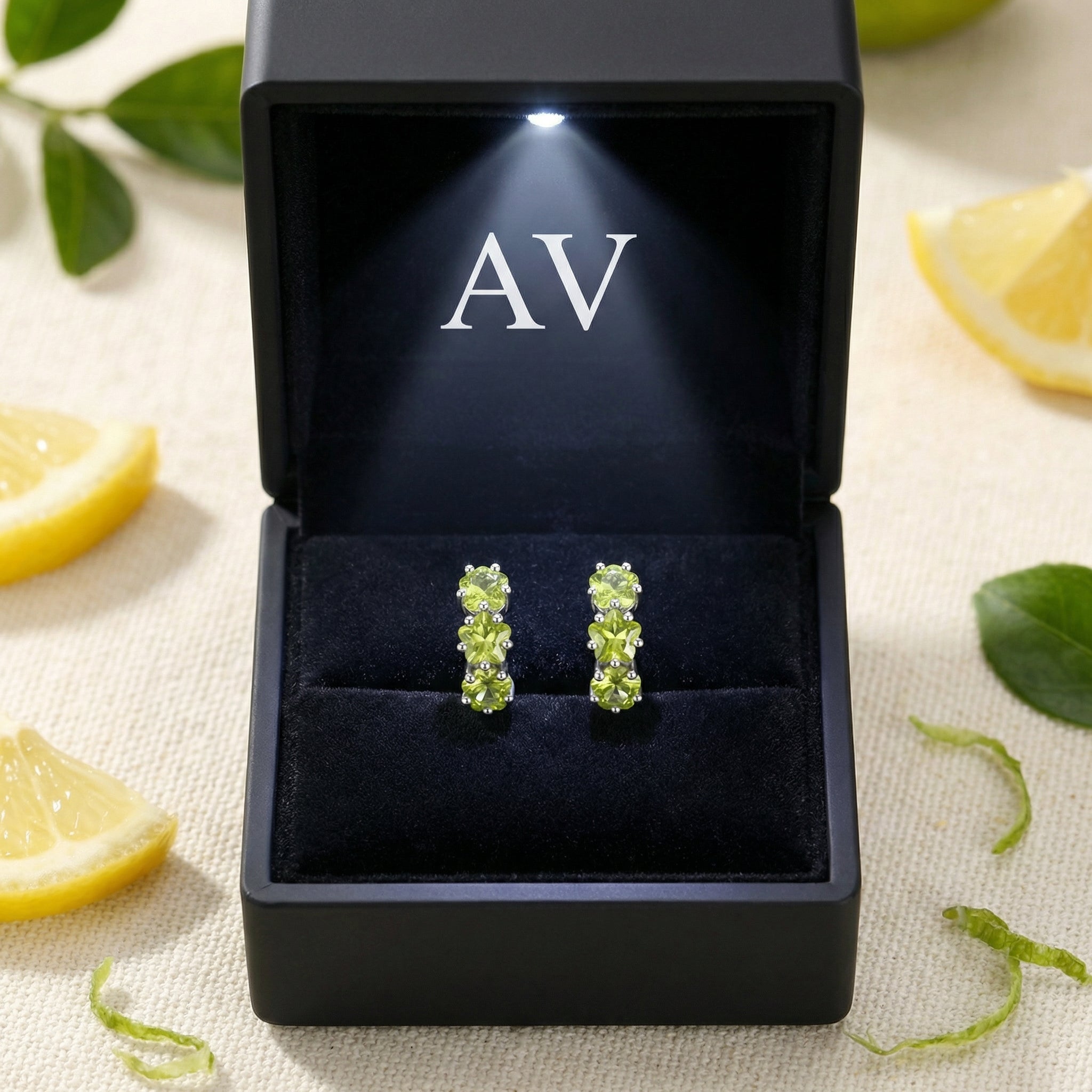 Sterling silver star hoop earrings with peridot stones presented in a black illuminated gift box with lemons.