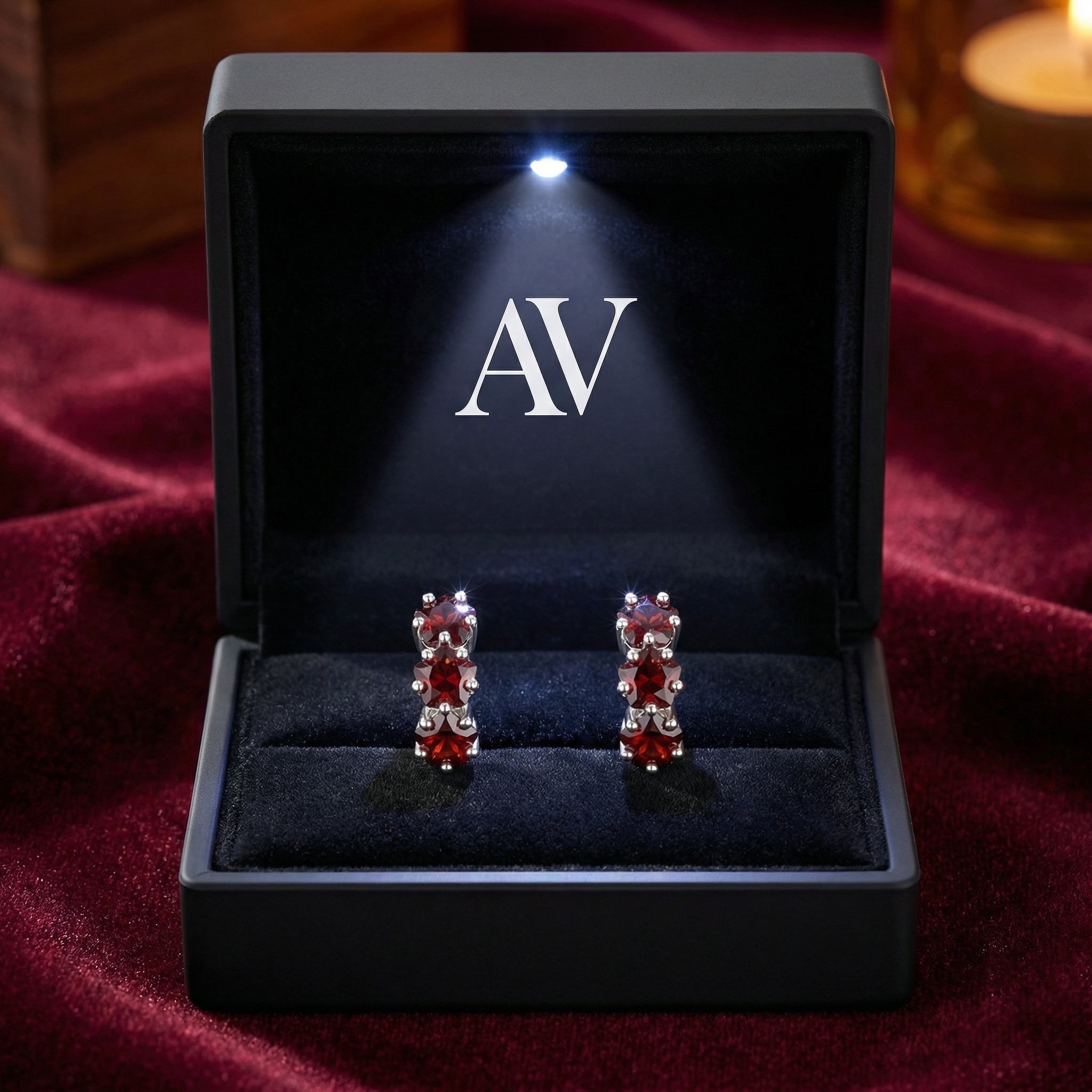 S925 sterling silver star-cut simulated garnet huggie earrings in a lighted black jewelry gift box.