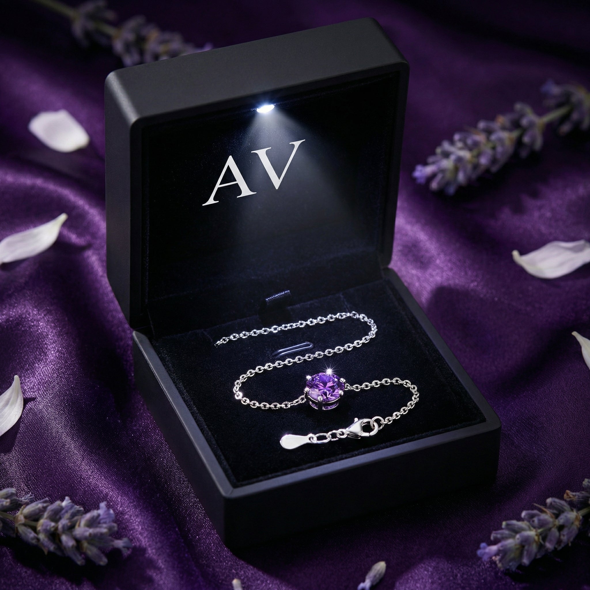 Amethyst solitaire sterling silver bracelet inside a black LED-lit gift box on purple silk with lavender.
