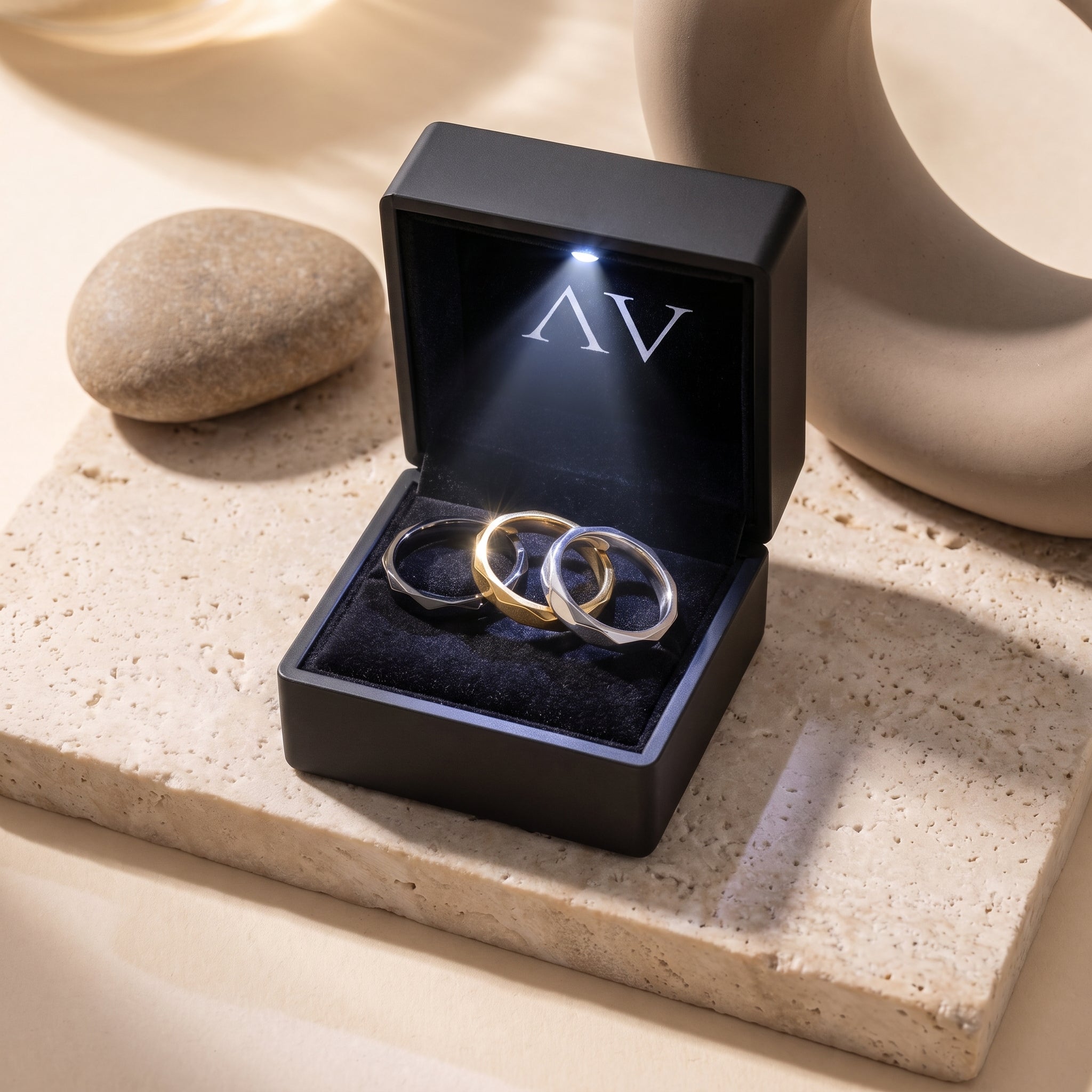 Black, gold, and silver faceted rings presented in a premium lighted black jewelry box.