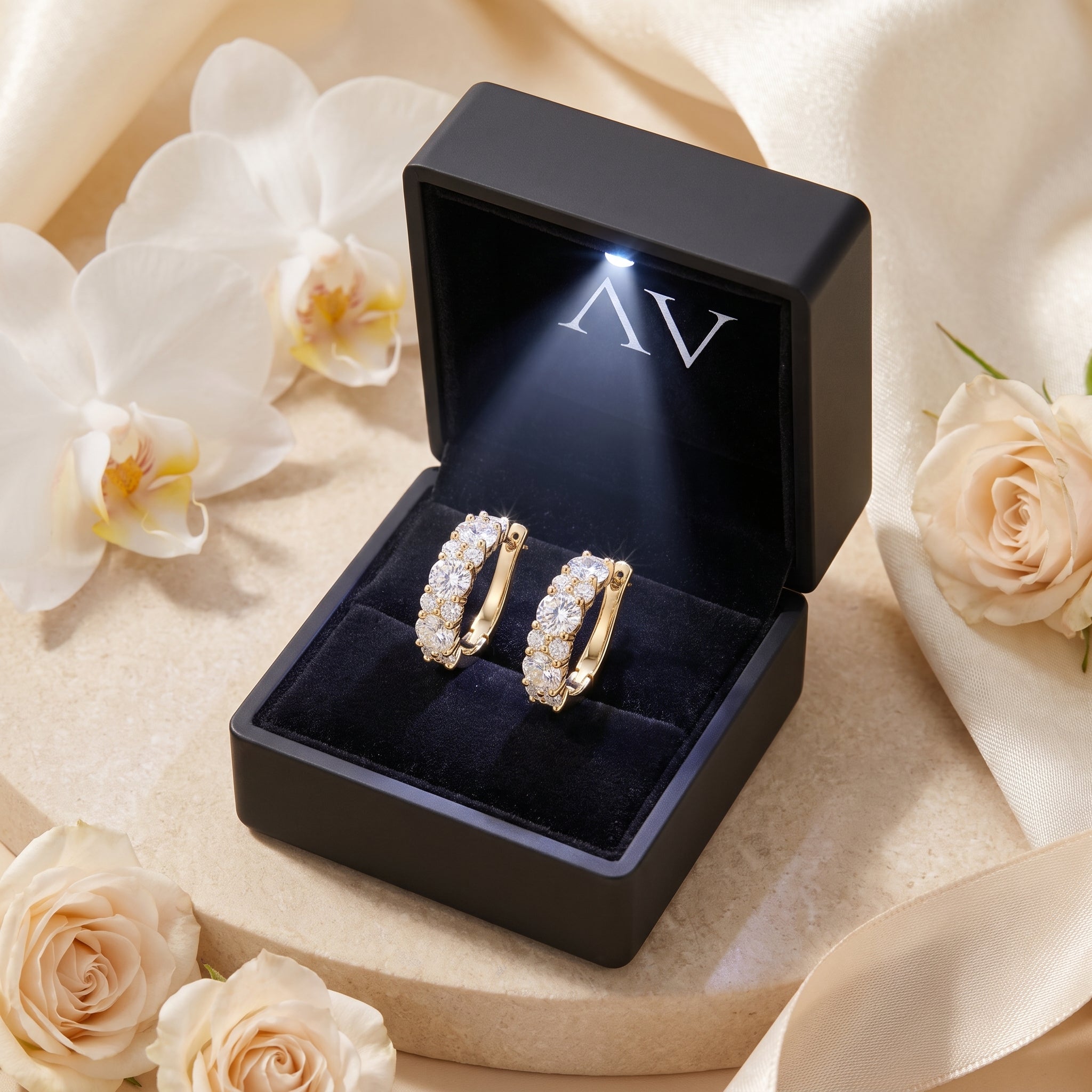 Gold moissanite hoop earrings in a black LED-lit gift box.
