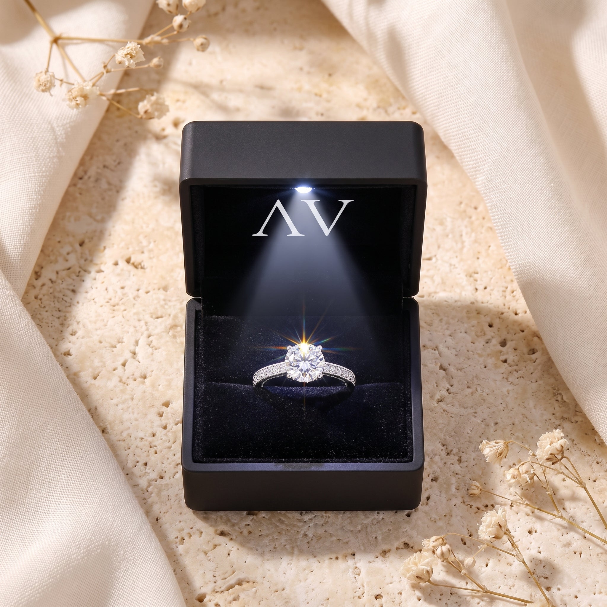 Calliandra sterling silver ring with a sparkling round-cut stone in a lighted black presentation box.