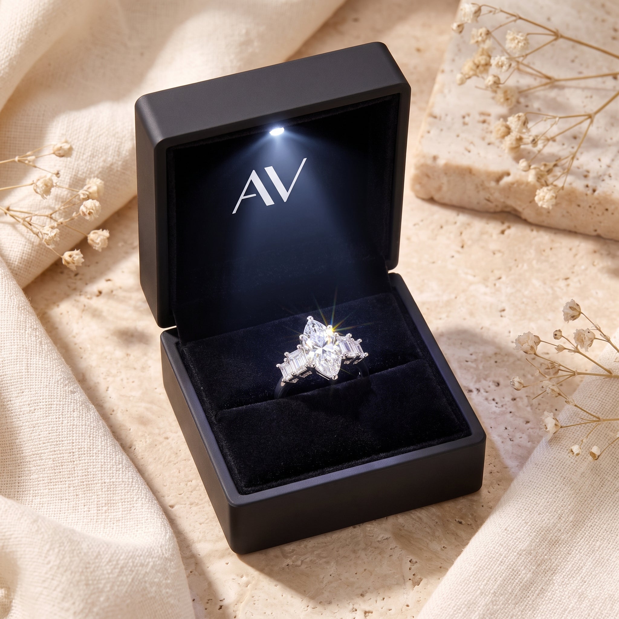 Silver marquise-cut ring inside a black lighted presentation box.