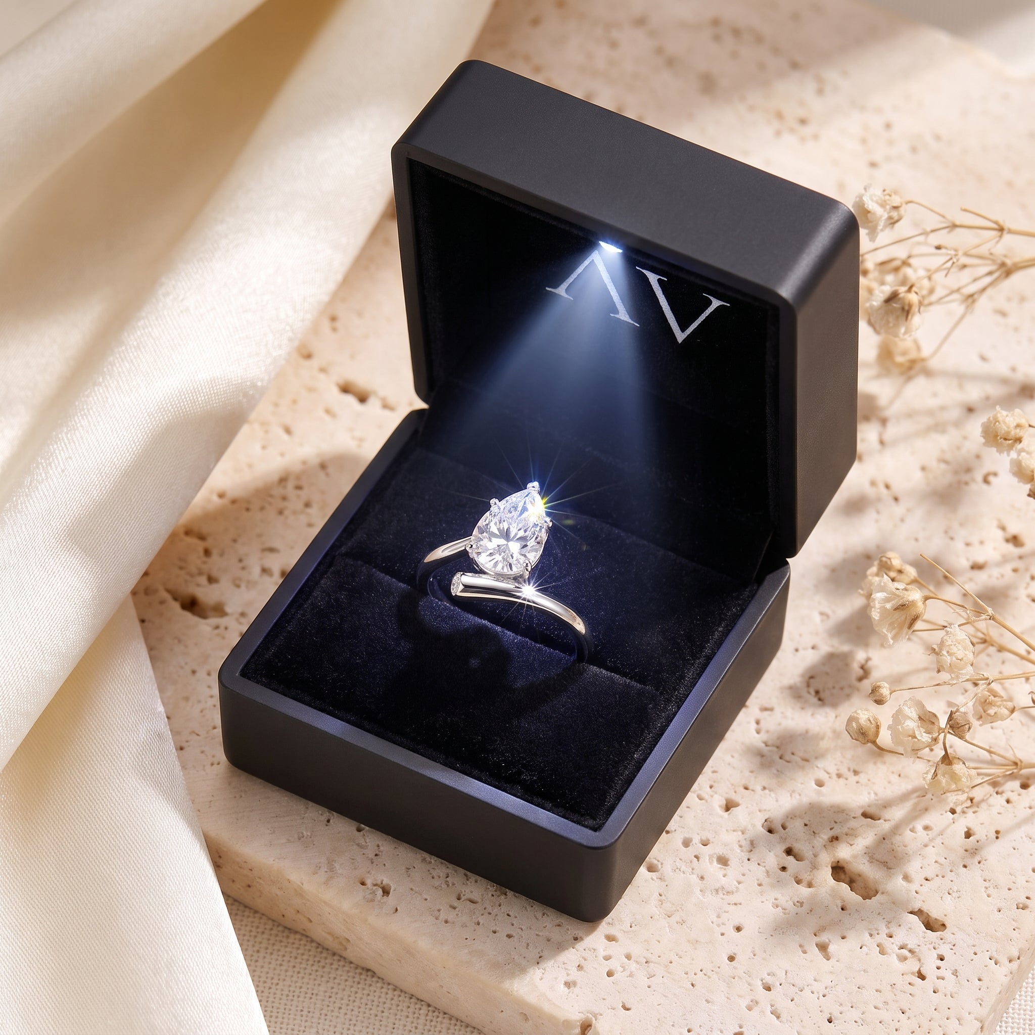 Pear-cut simulated diamond bypass ring inside a black LED-lit jewelry box.