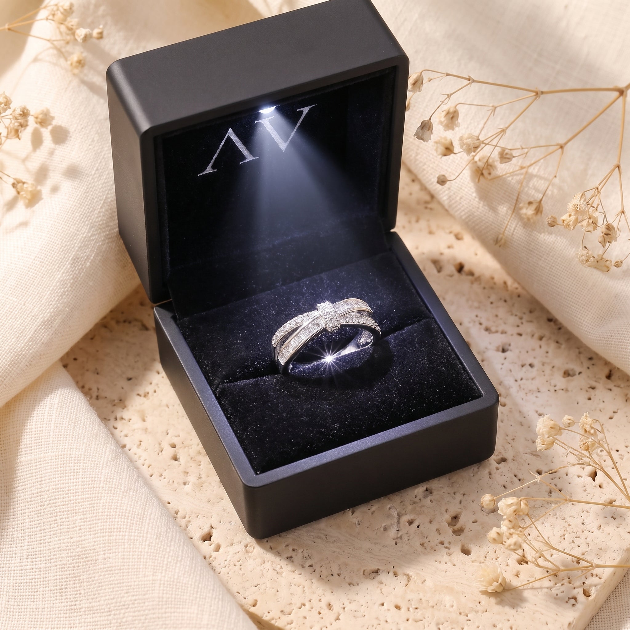 Charlotte silver ribbon ring with simulated diamonds inside a lighted black jewelry presentation box.