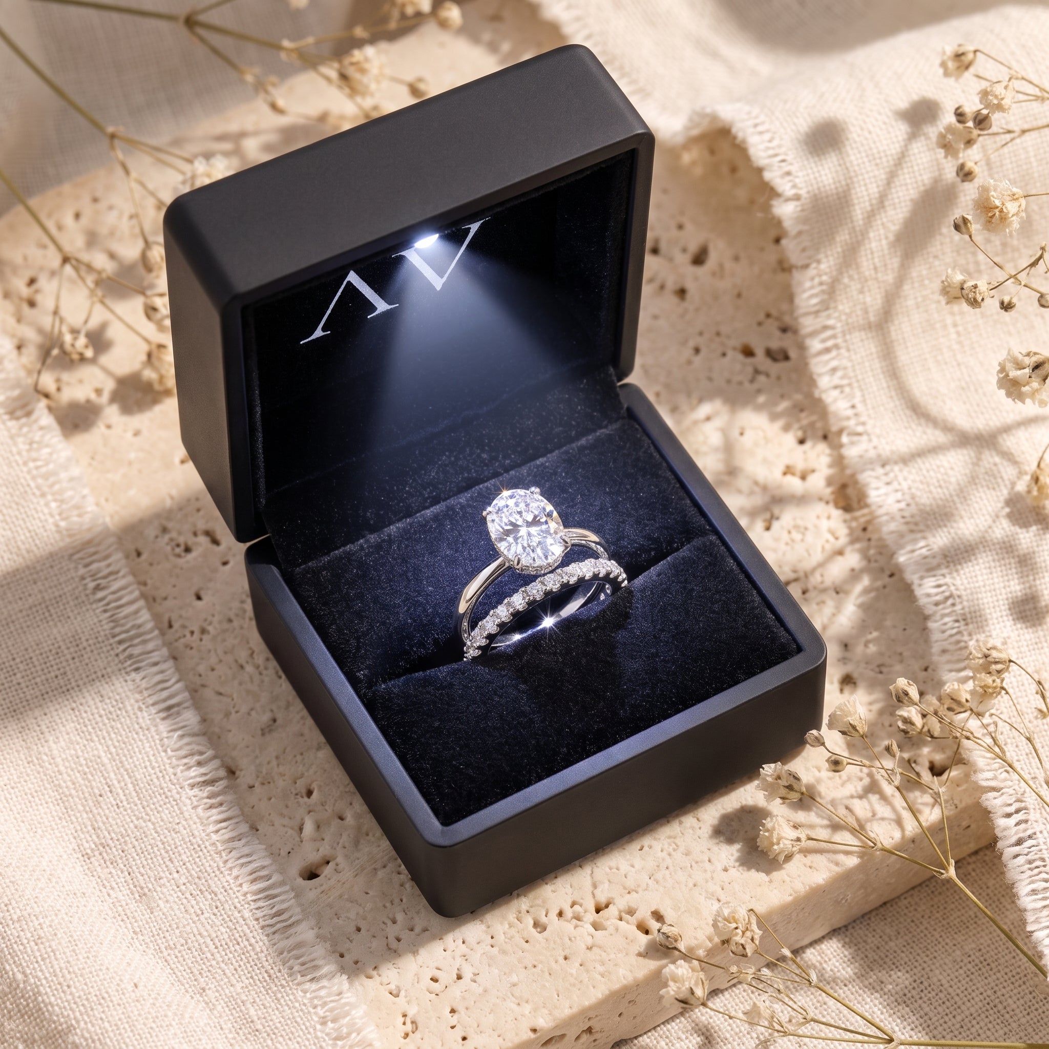 Oval-cut simulated diamond ring set in a lighted black jewelry box.