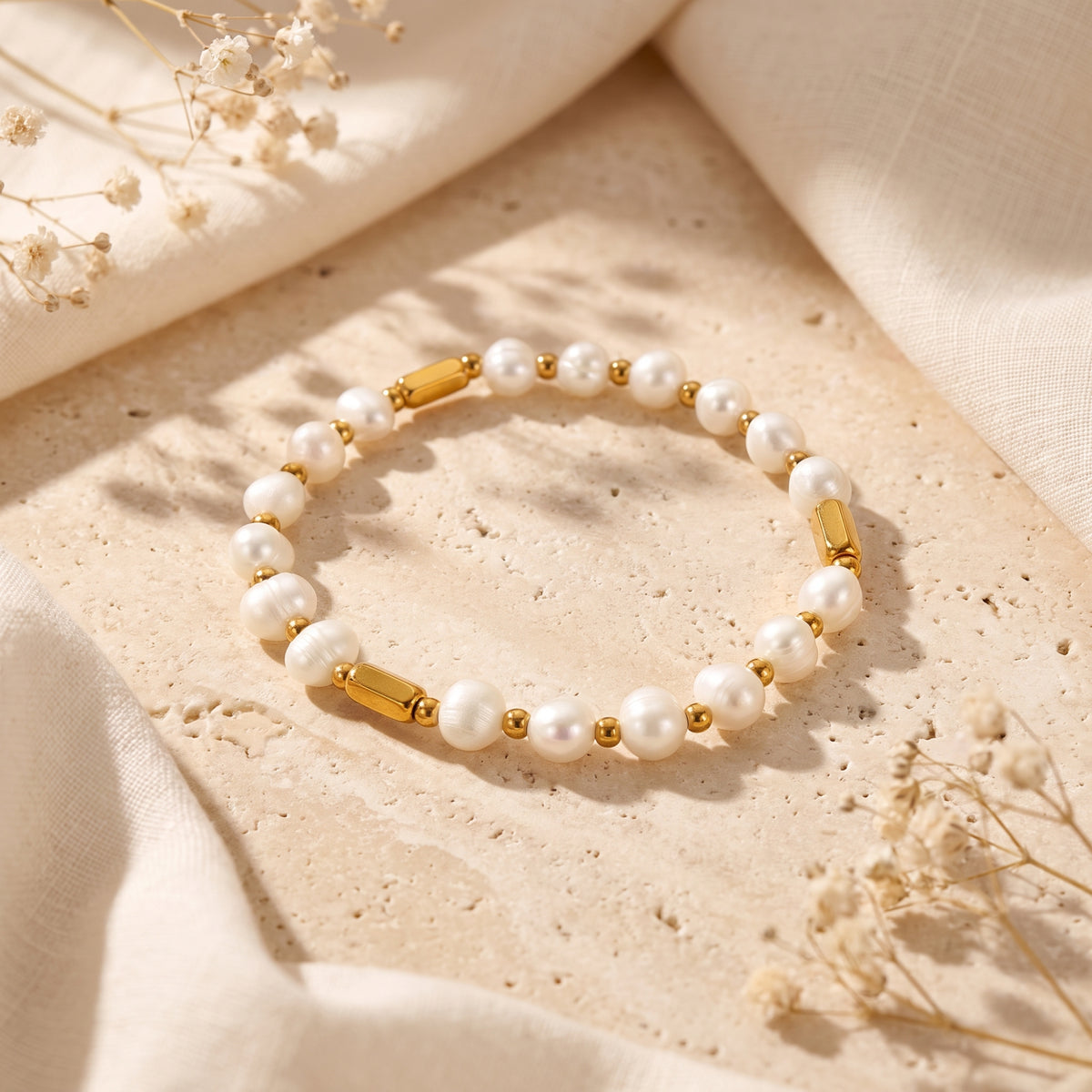 Pearl Station Bracelet with white pearls and gold-color bar accents laid flat on a textured stone surface.