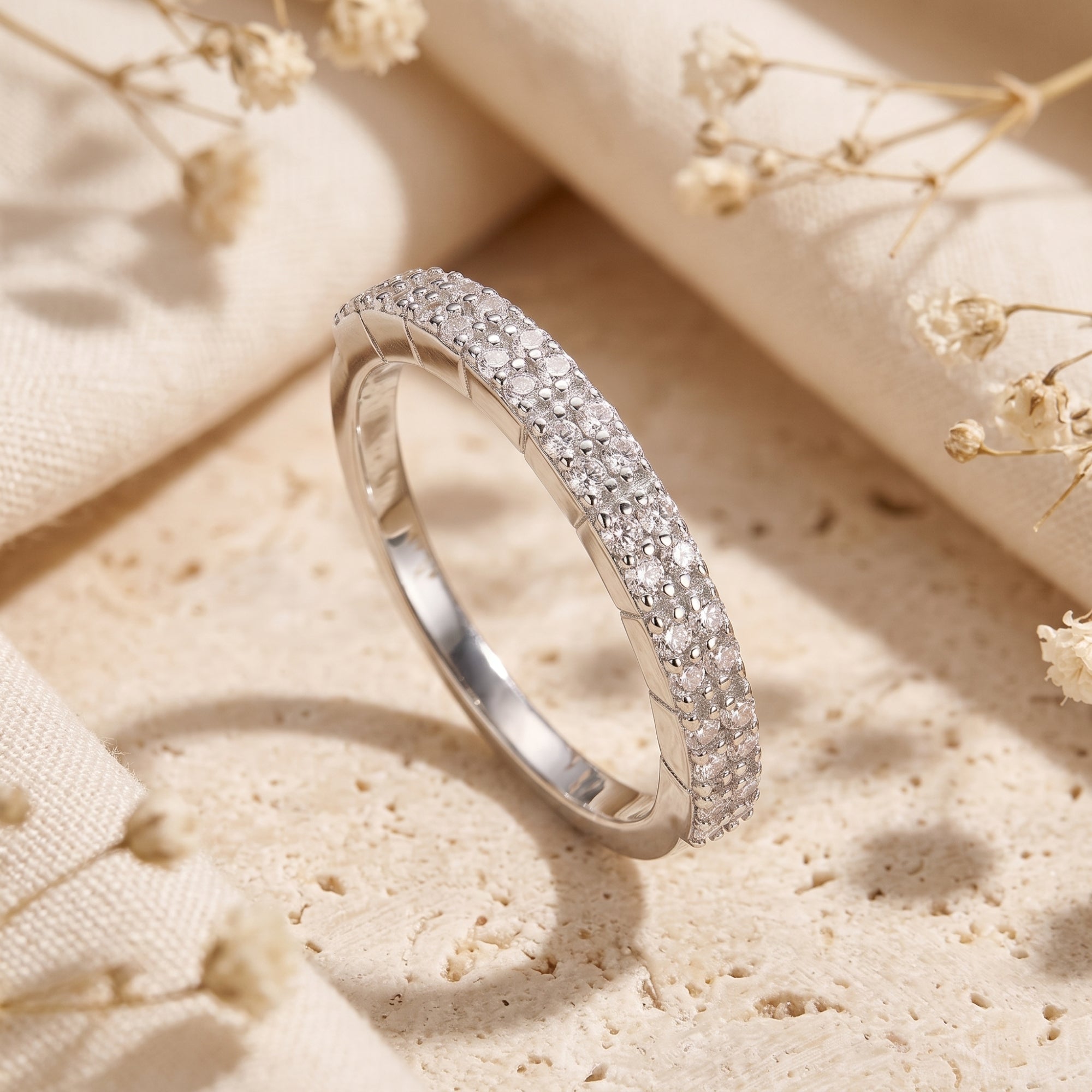 Double row pavé sterling silver ring with cubic zirconia on a lifestyle stone background.