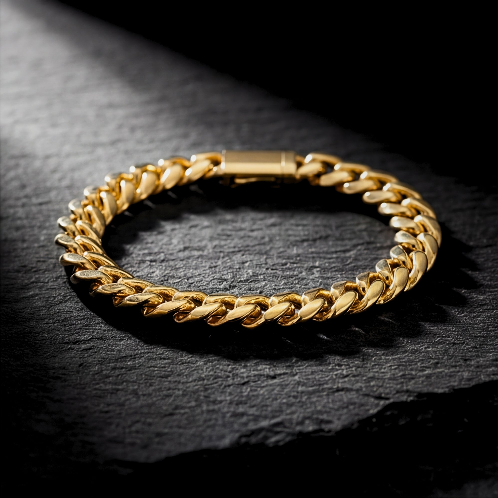 8mm gold stainless steel Cuban link bracelet resting on a dark textured stone surface.