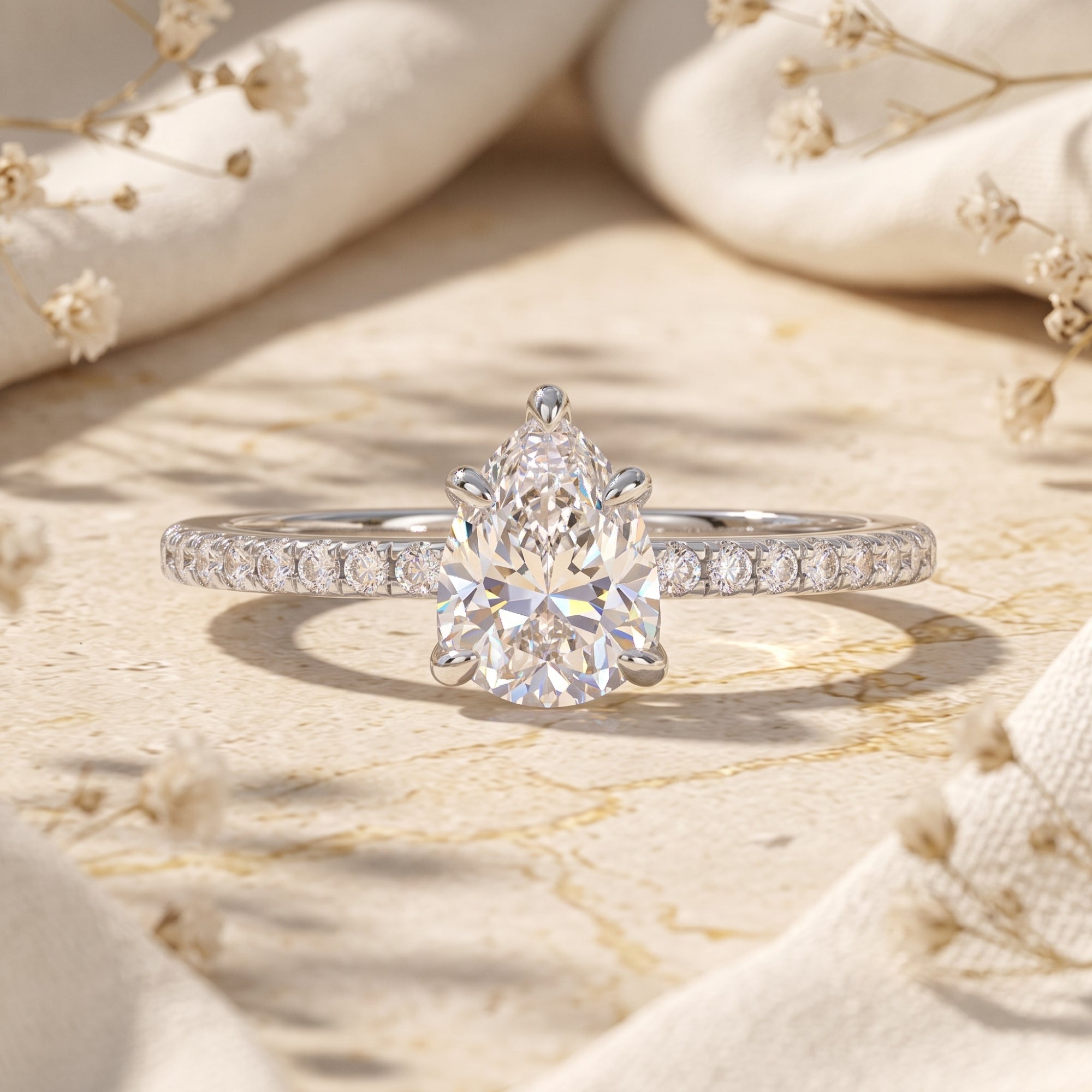 Pear cut cubic zirconia ring in S925 sterling silver on a textured stone surface with dried flowers.