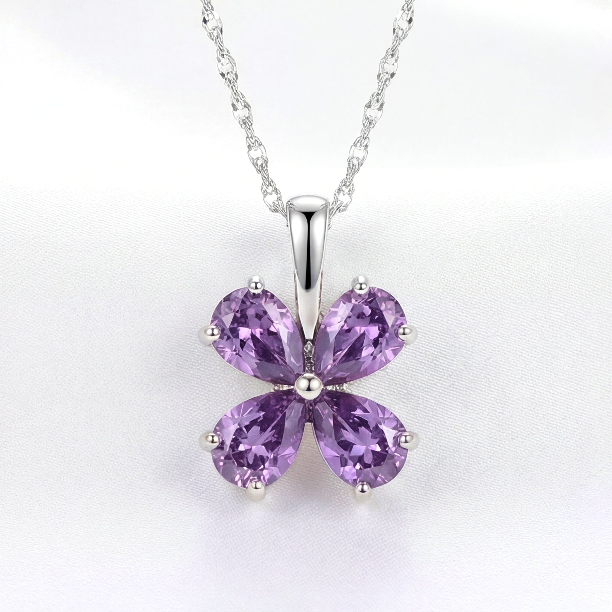 Amity clover necklace in S925 sterling silver with heart-cut simulated amethysts on a white fabric background.